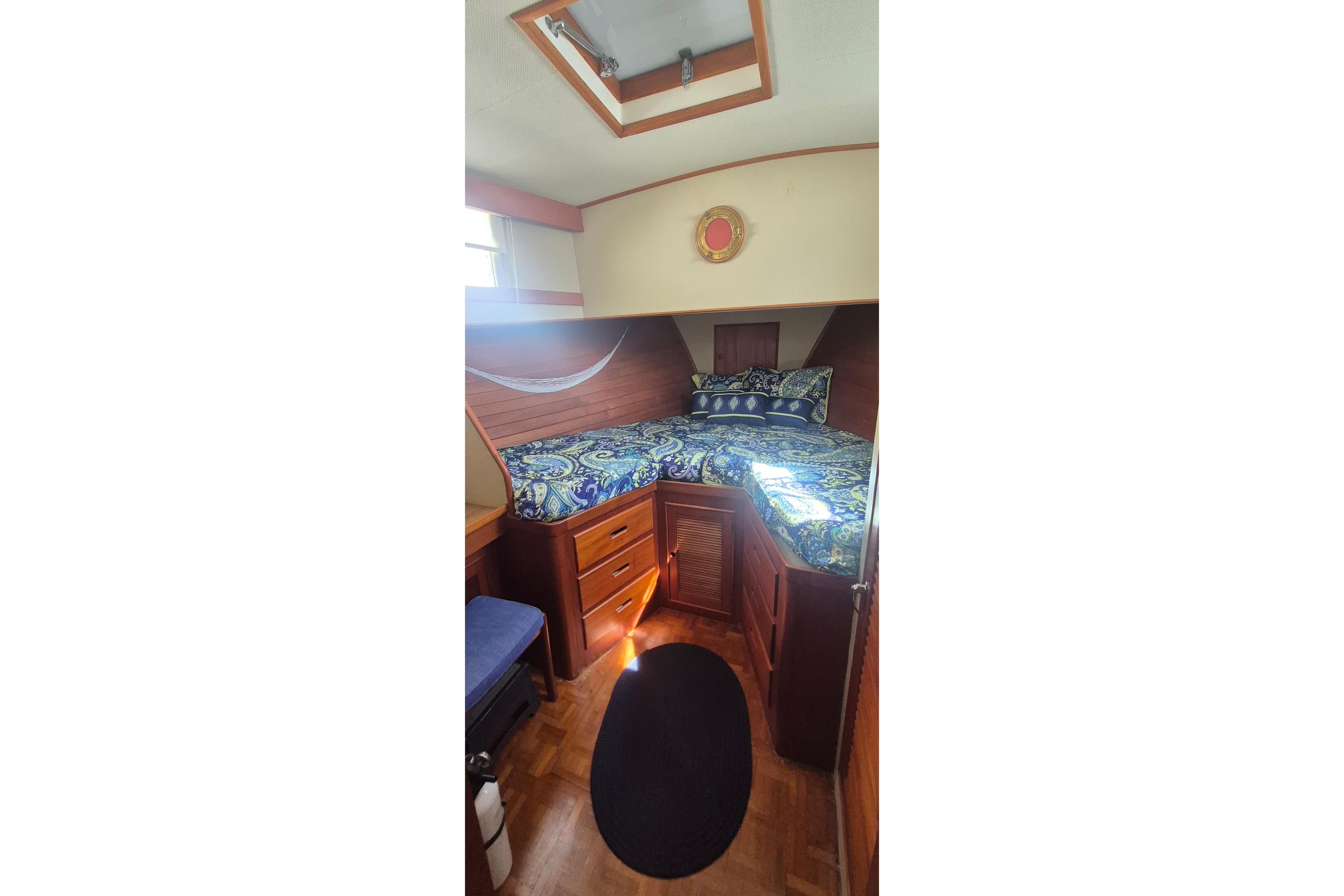 Cozy cabin interior of 1983 Grand Banks 42 Motoryacht with patterned bedding and wooden furnishings.