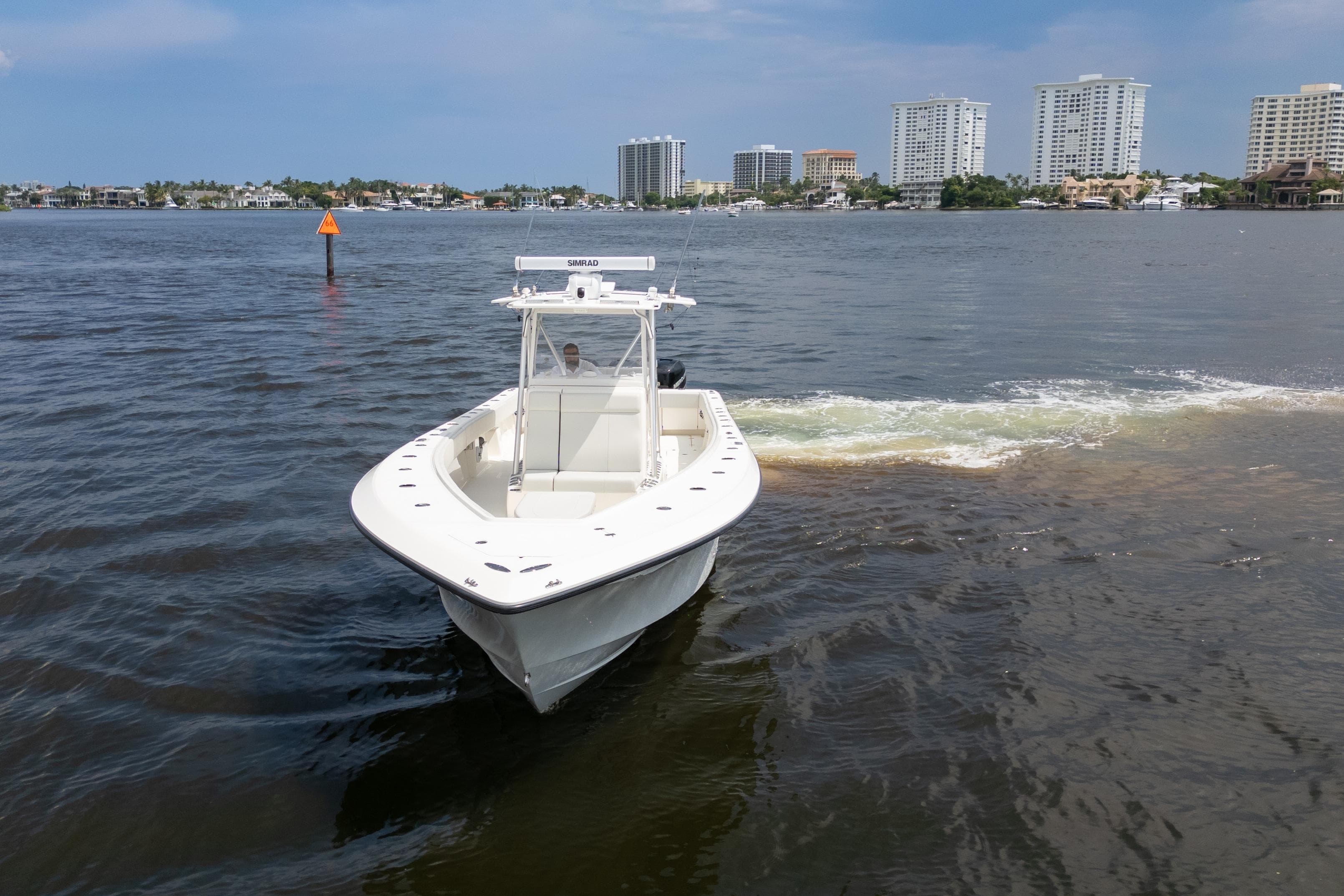 2015 SeaVee 39Z boat cruising on a calm waterway with city skyline in background.