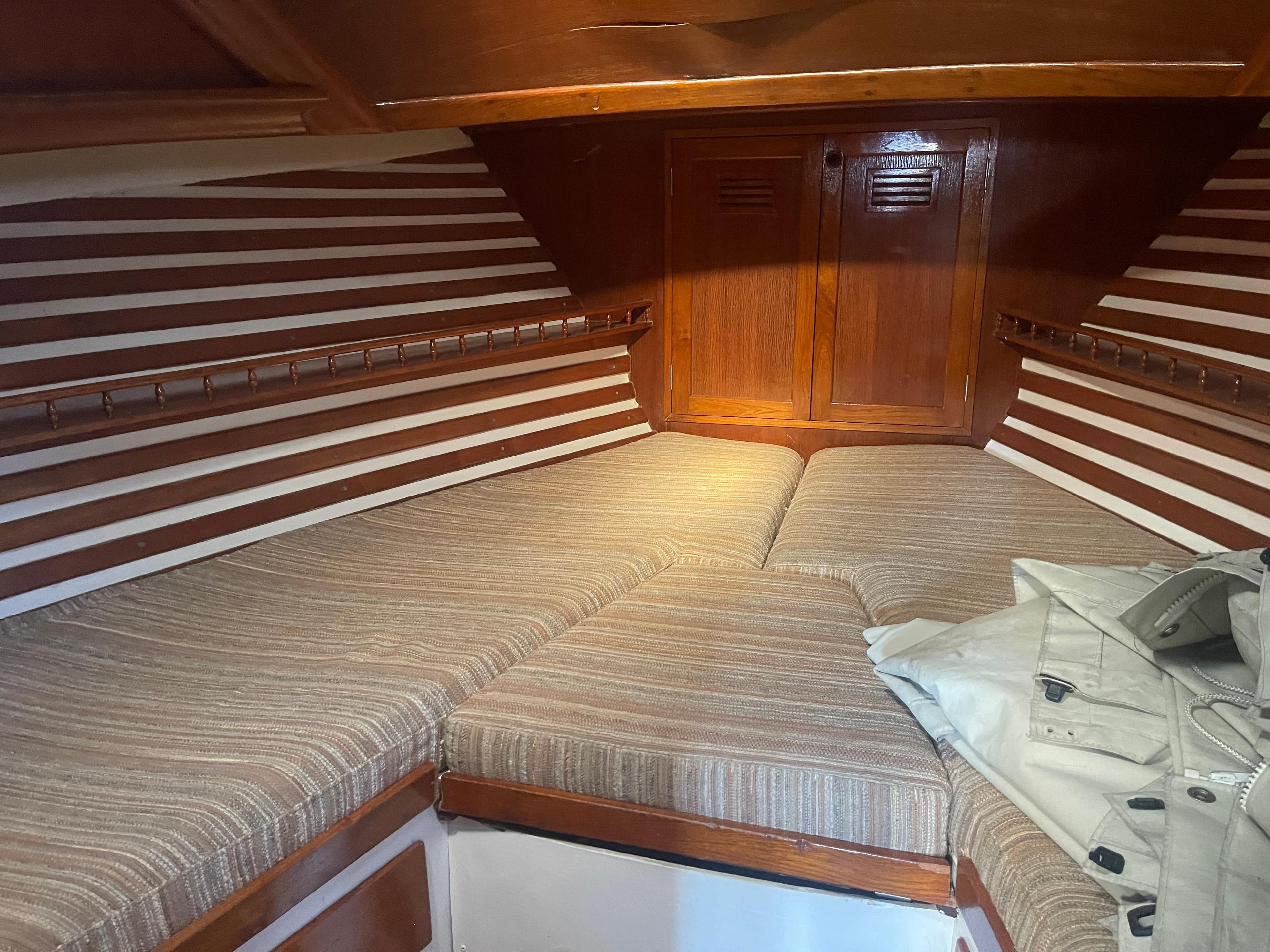 1976 Cheoy Lee Clipper 42 interior cabin with striped cushions and wooden paneling.