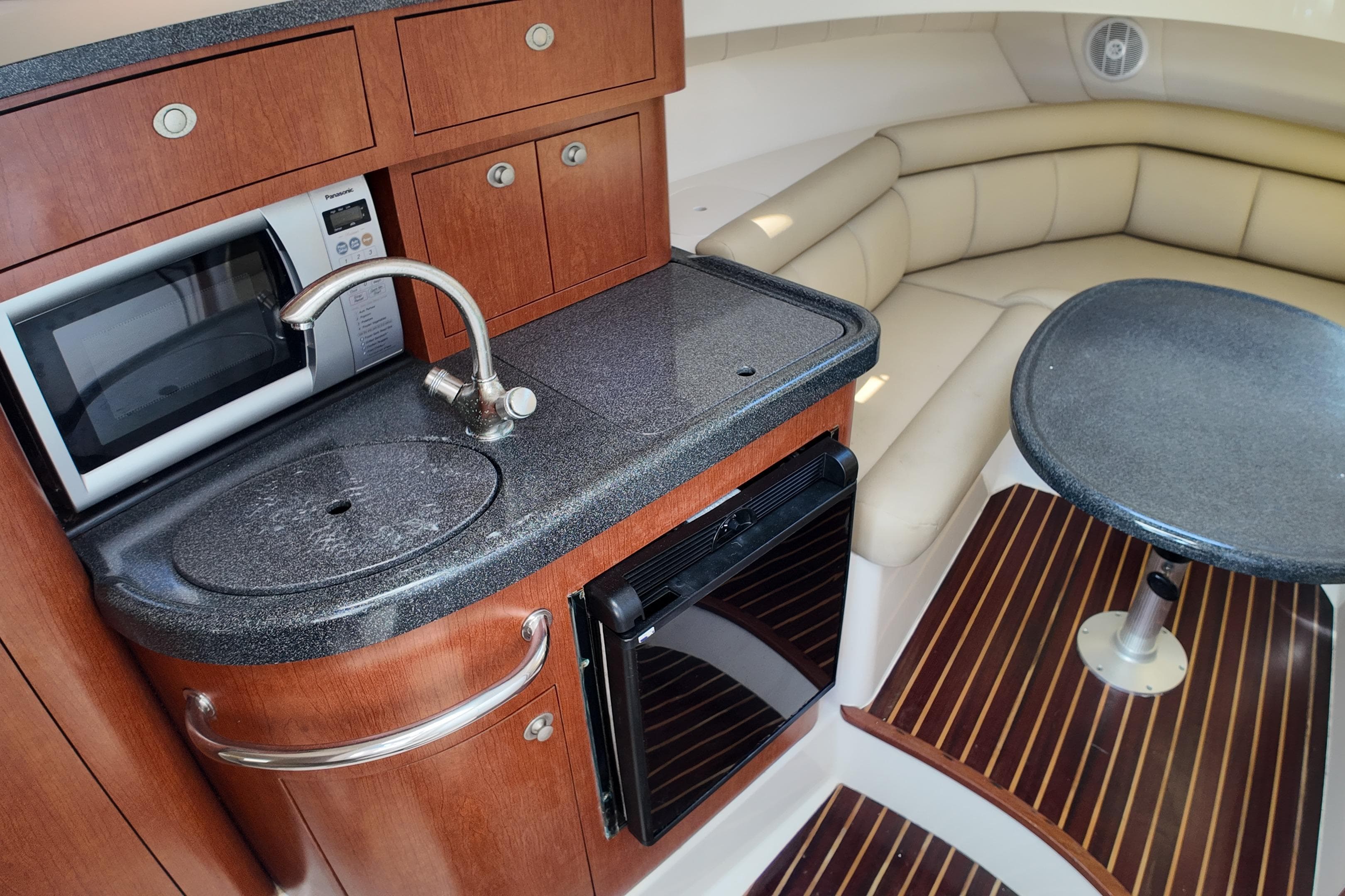 2005 Boston Whaler 305 Conquest interior with kitchenette, microwave, sink, and seating area.