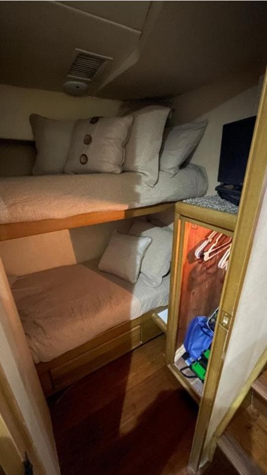 Bunk beds in a 1995 Bertram Convertible yacht cabin with pillows and a small closet.