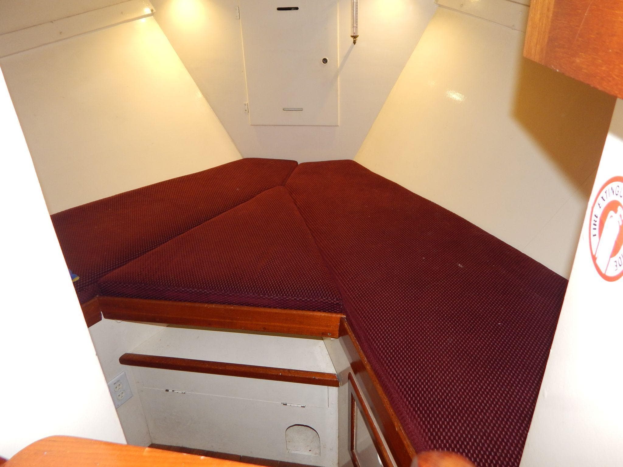Interior cabin of 1963 Grand Banks 35 Chantyman with maroon cushions and wooden accents.