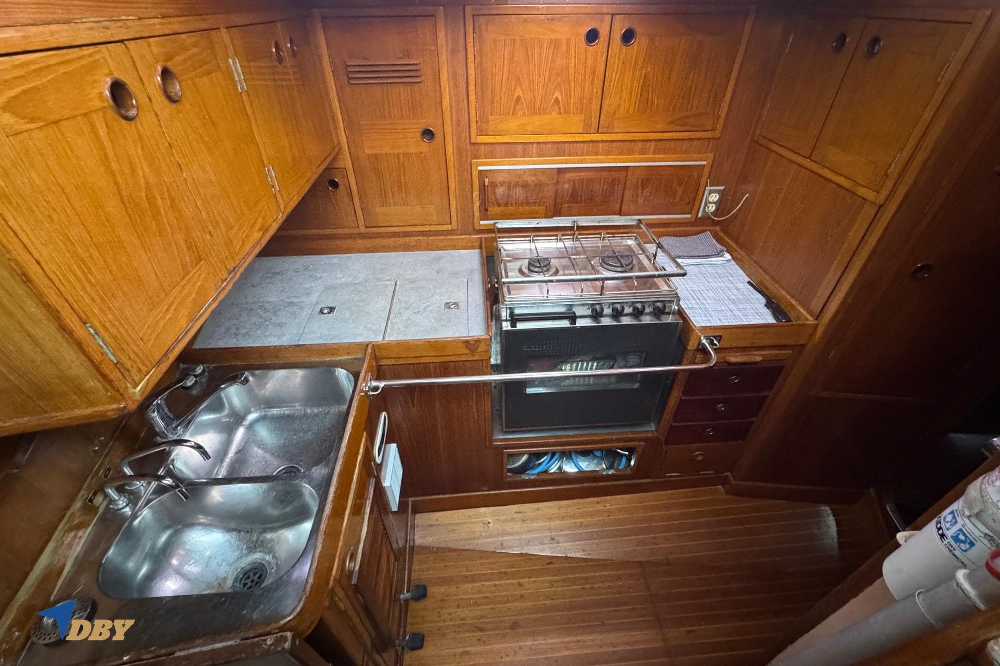 1981 Baltic 42 yacht kitchen with wooden cabinets, dual sink, and stove.