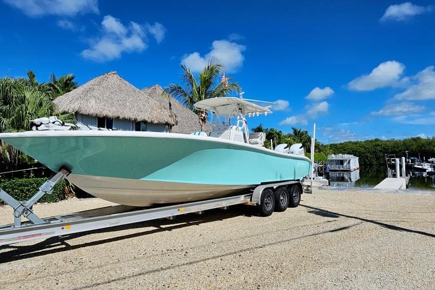 2002 Yellowfin 31 Center Console boat on trailer, tropical setting, clear blue sky.