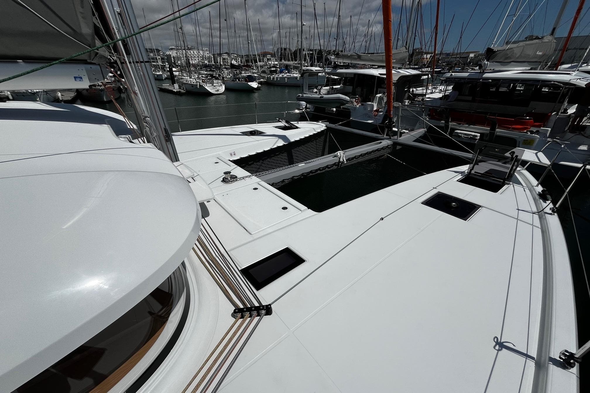 2025 Excess EXCESS 14 catamaran docked in a marina, surrounded by other boats.