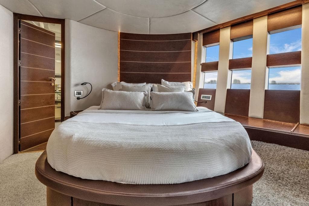 Luxurious bedroom interior of 2006 Azimut 68S yacht with modern design and large windows.