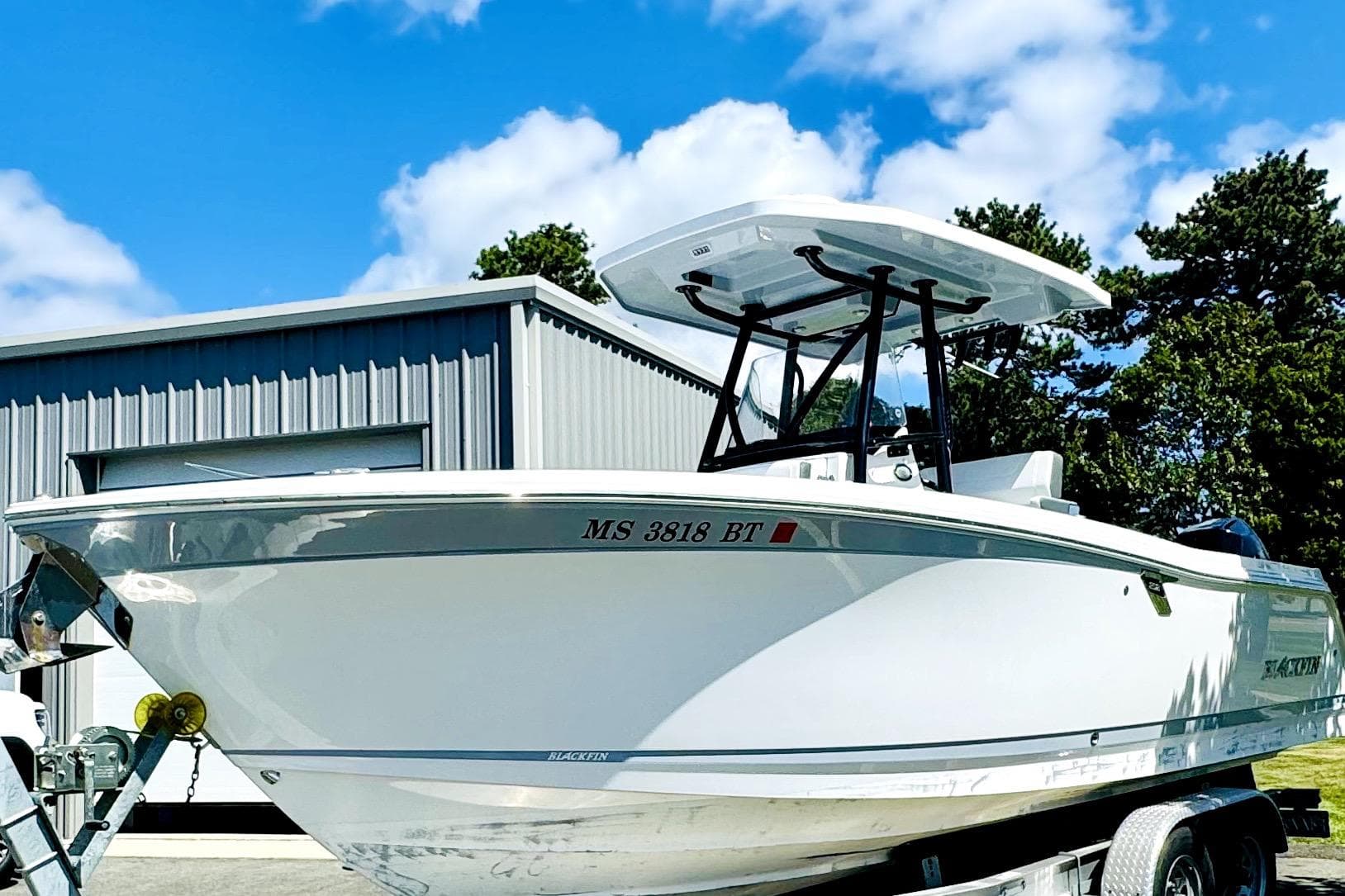2022 Blackfin 252 CC boat on trailer, parked near a metal building under a blue sky.