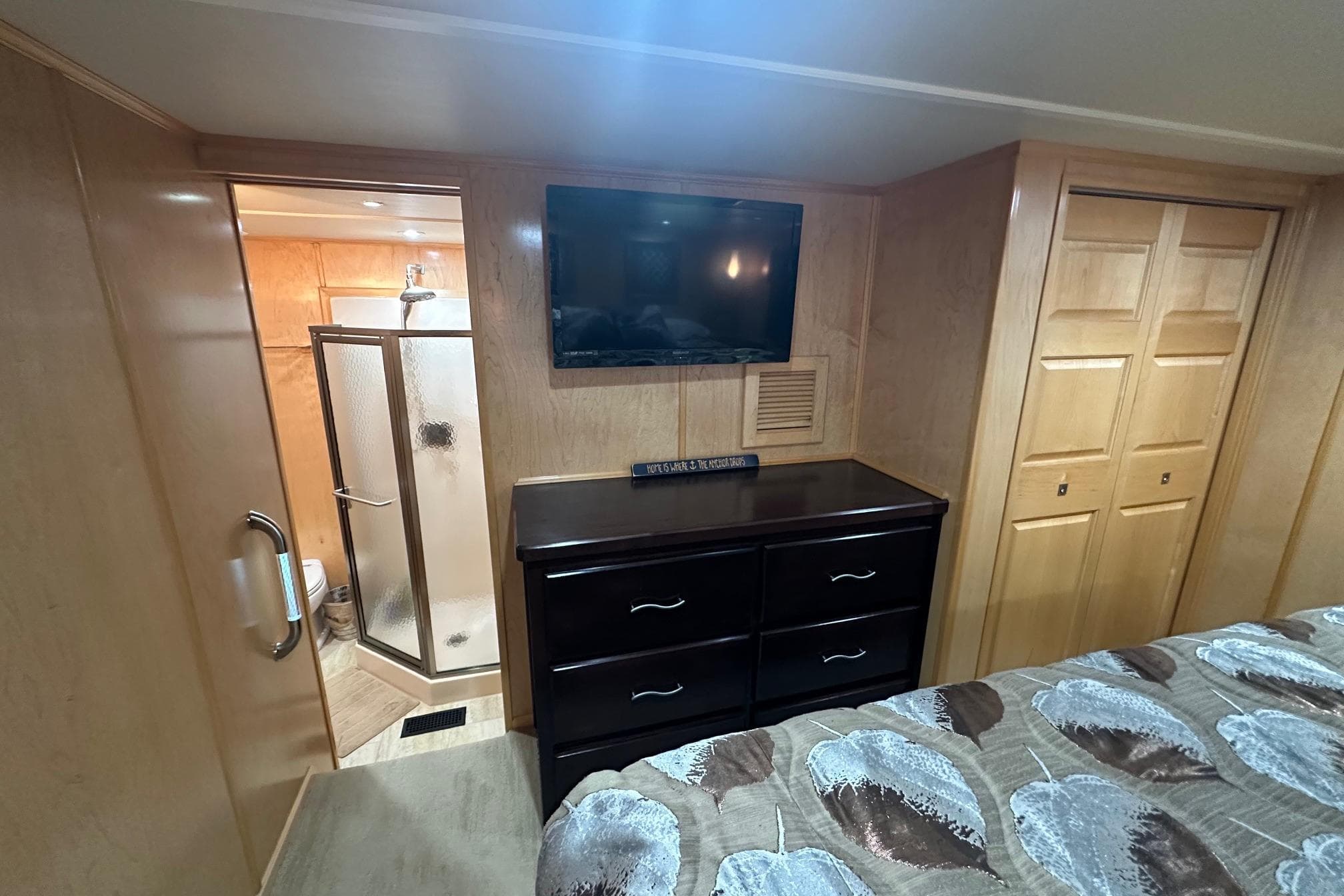 Bedroom interior of 2013 Sumerset 18x85 houseboat with TV, dresser, and ensuite bathroom.