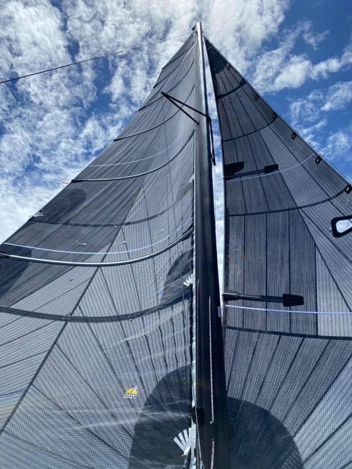 Sail of a 2025 Corsair 880 against a blue sky with clouds.