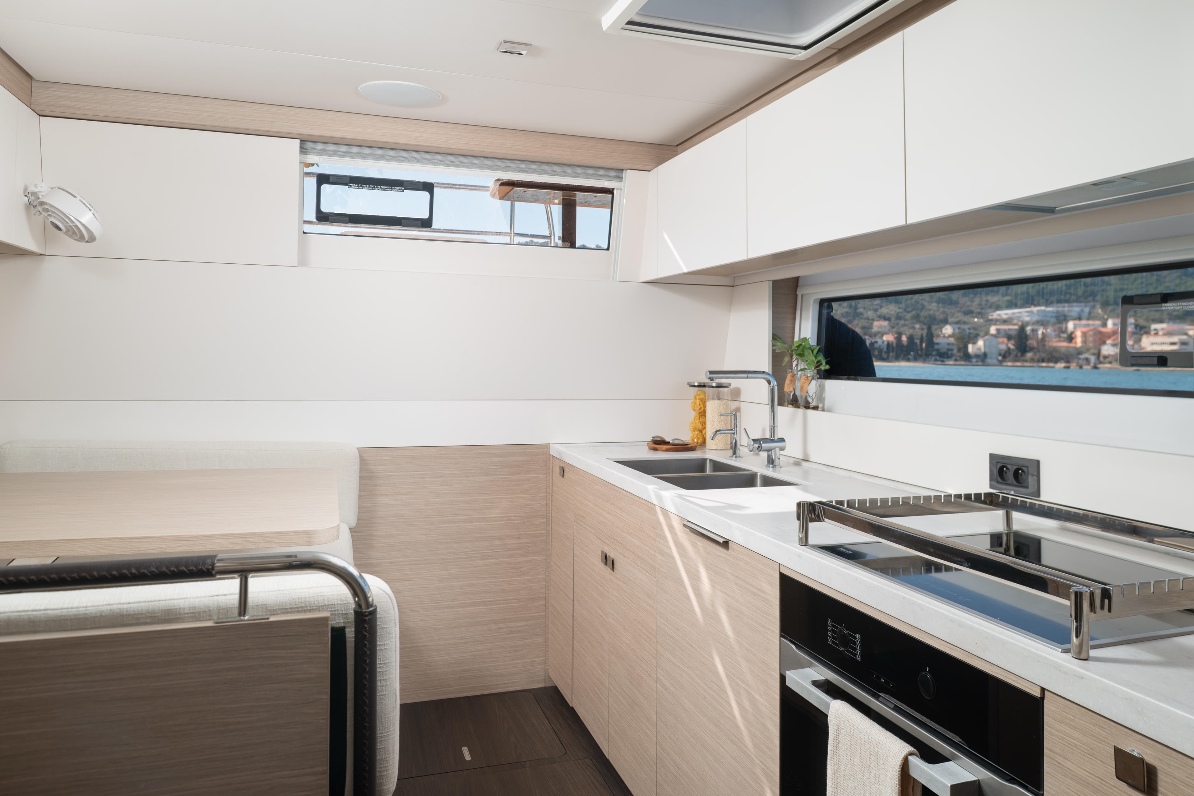 Modern kitchen interior of 2025 Lagoon 60 yacht with sleek design and large windows.