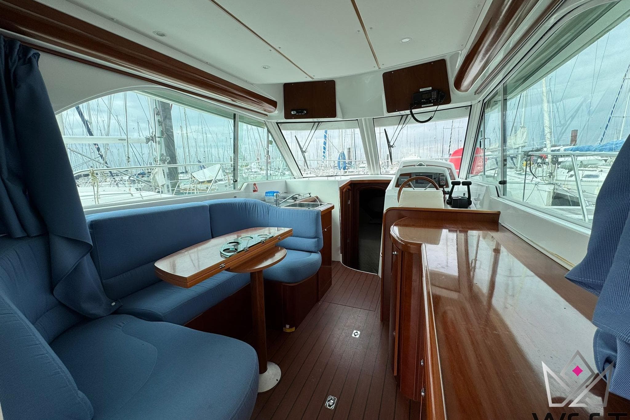 Interior of 2006 Beneteau Antares 9.80 yacht with blue seating and wooden finishes.