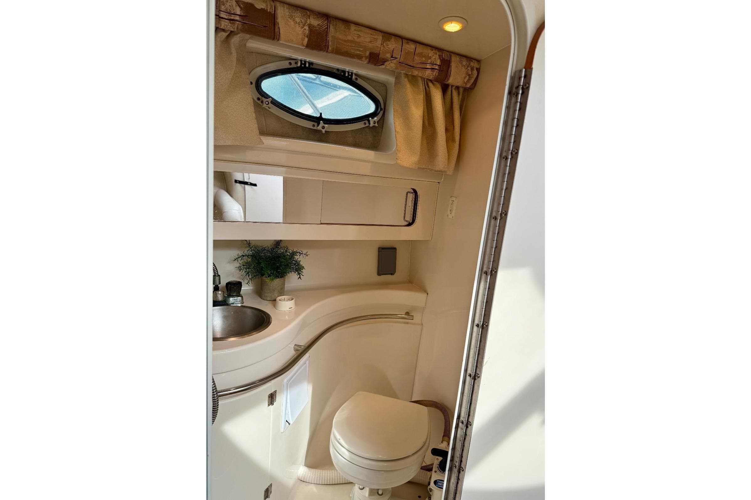 1999 Monterey 296 Cruiser bathroom with sink, toilet, and porthole window.