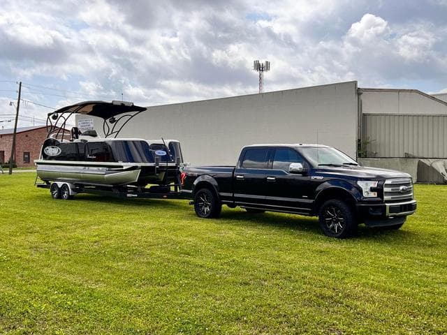 Aloha 2025 23' Paradise Arch Sport Tower boat towed by a black pickup truck.