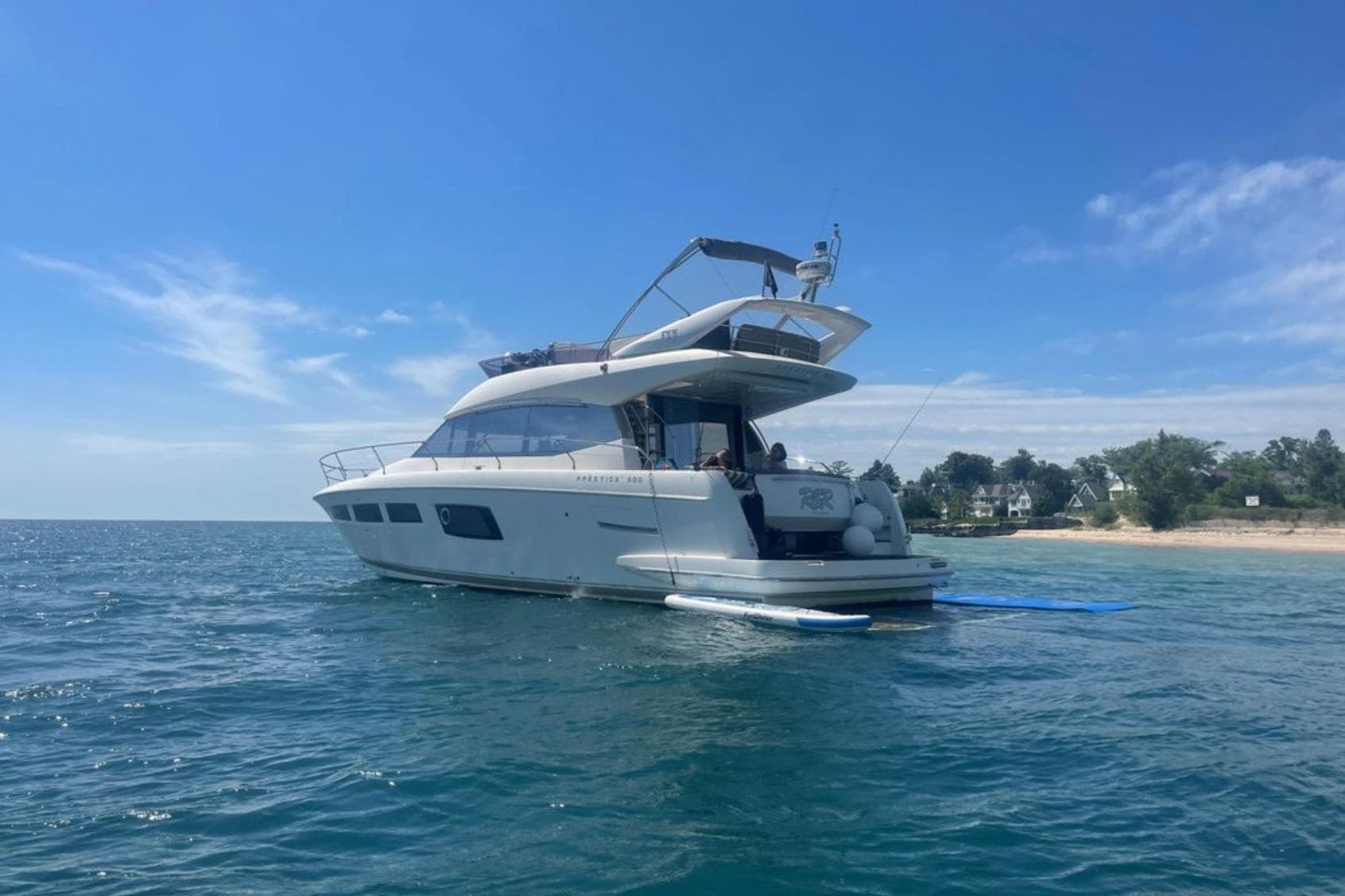 2012 Prestige 500 yacht on calm sea near a sandy shoreline.