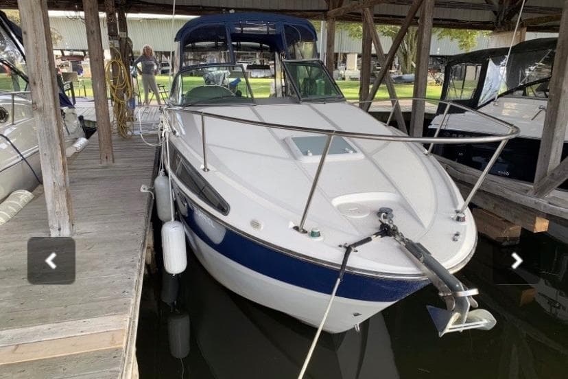 2008 Bayliner 265 boat docked in a marina, featuring a sleek white and blue design.