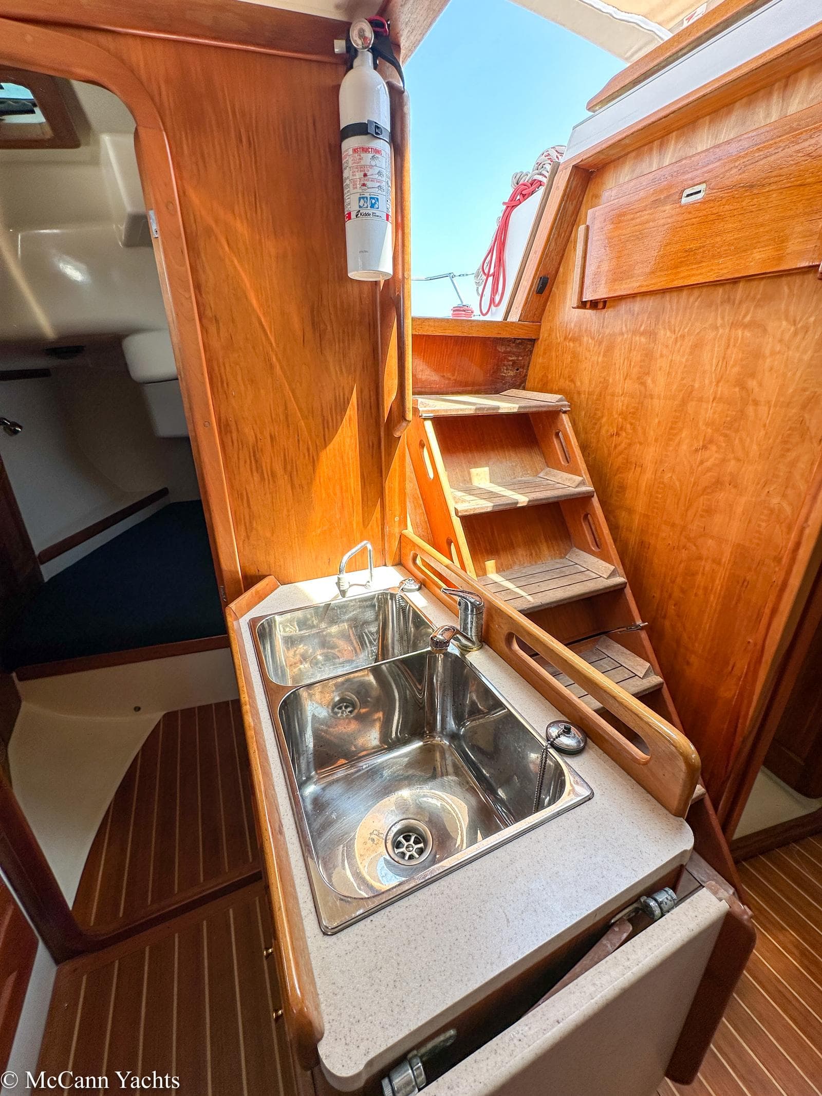 Compact galley in 2002 Tartan 3700 yacht with wooden cabinetry and stainless steel sink.