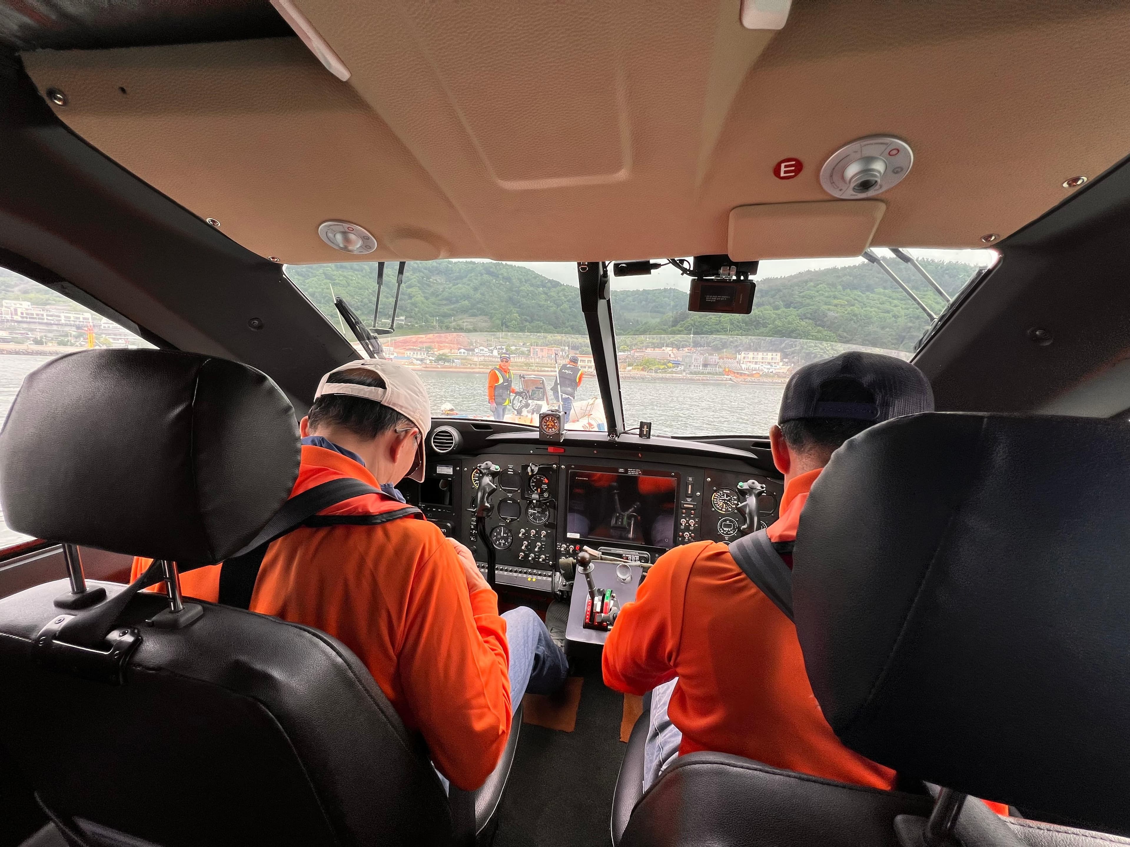 Cockpit view of Aron M 80 helicopter, 2025 model, with two pilots in orange uniforms.