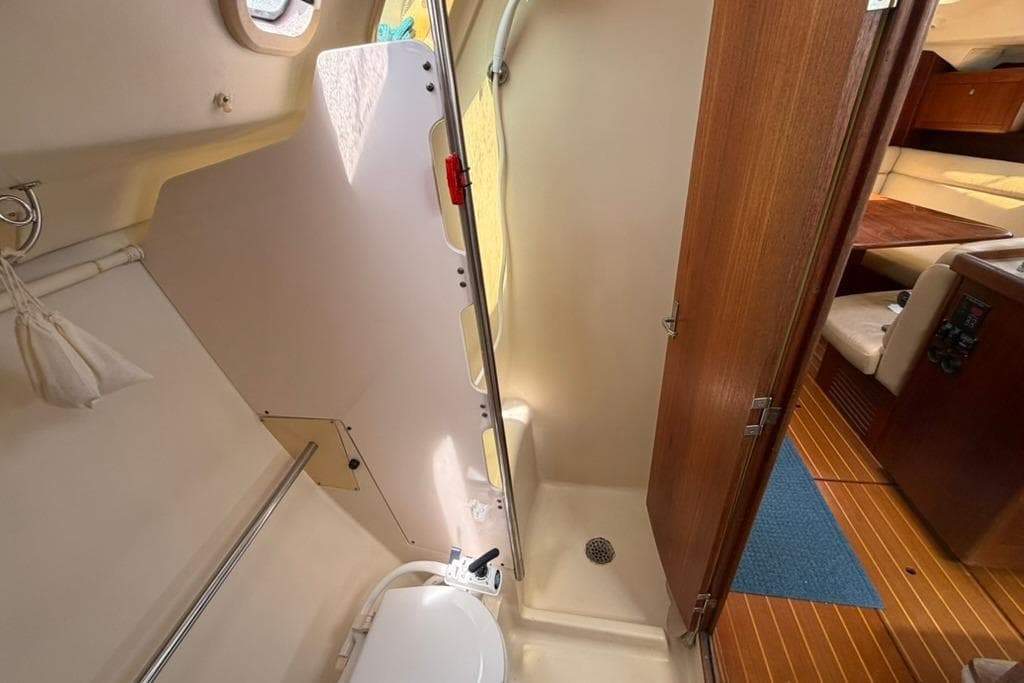 Interior of a 2002 Hunter 410 sailboat bathroom with shower and wooden door.
