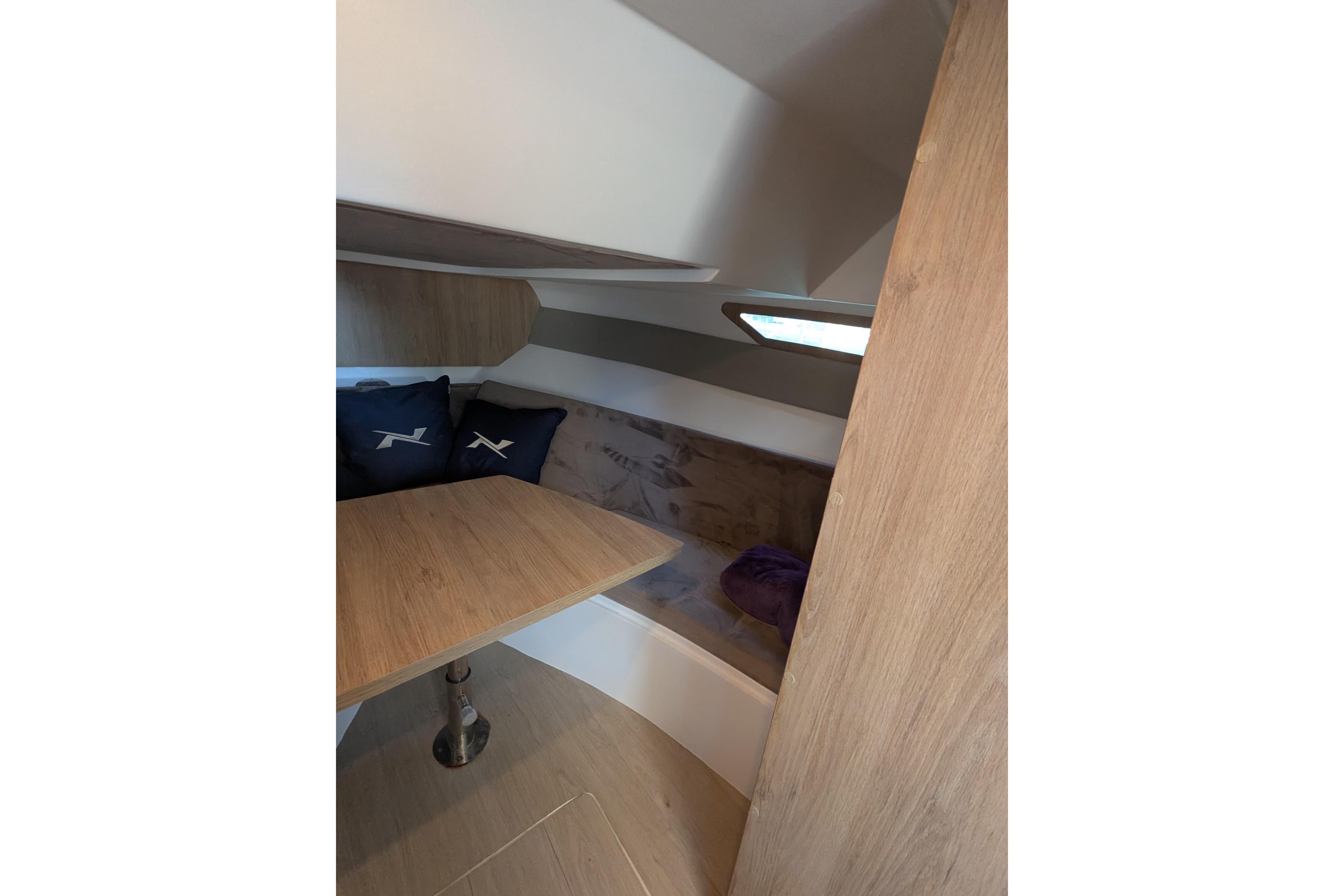 2023 NX Boats 340 Sport Coupe interior cabin with wooden table and seating area.