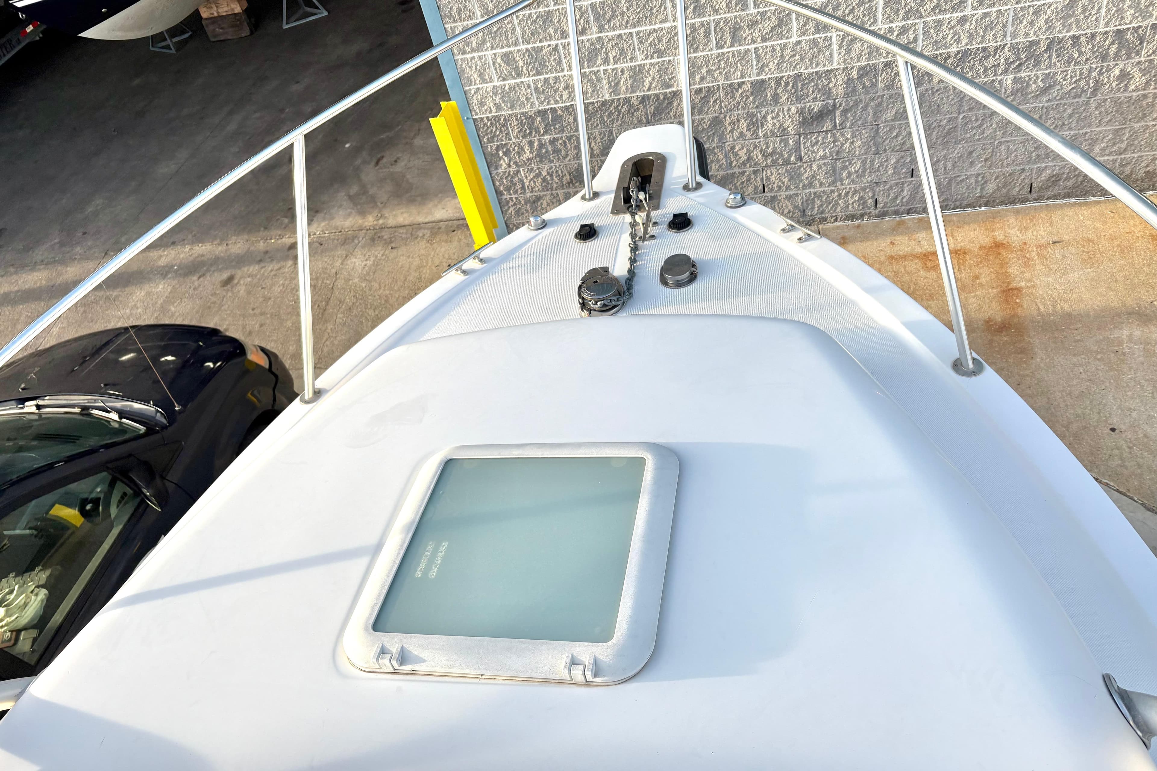 2006 Century 2400 Walkaround boat deck with anchor and hatch, docked near a vehicle.