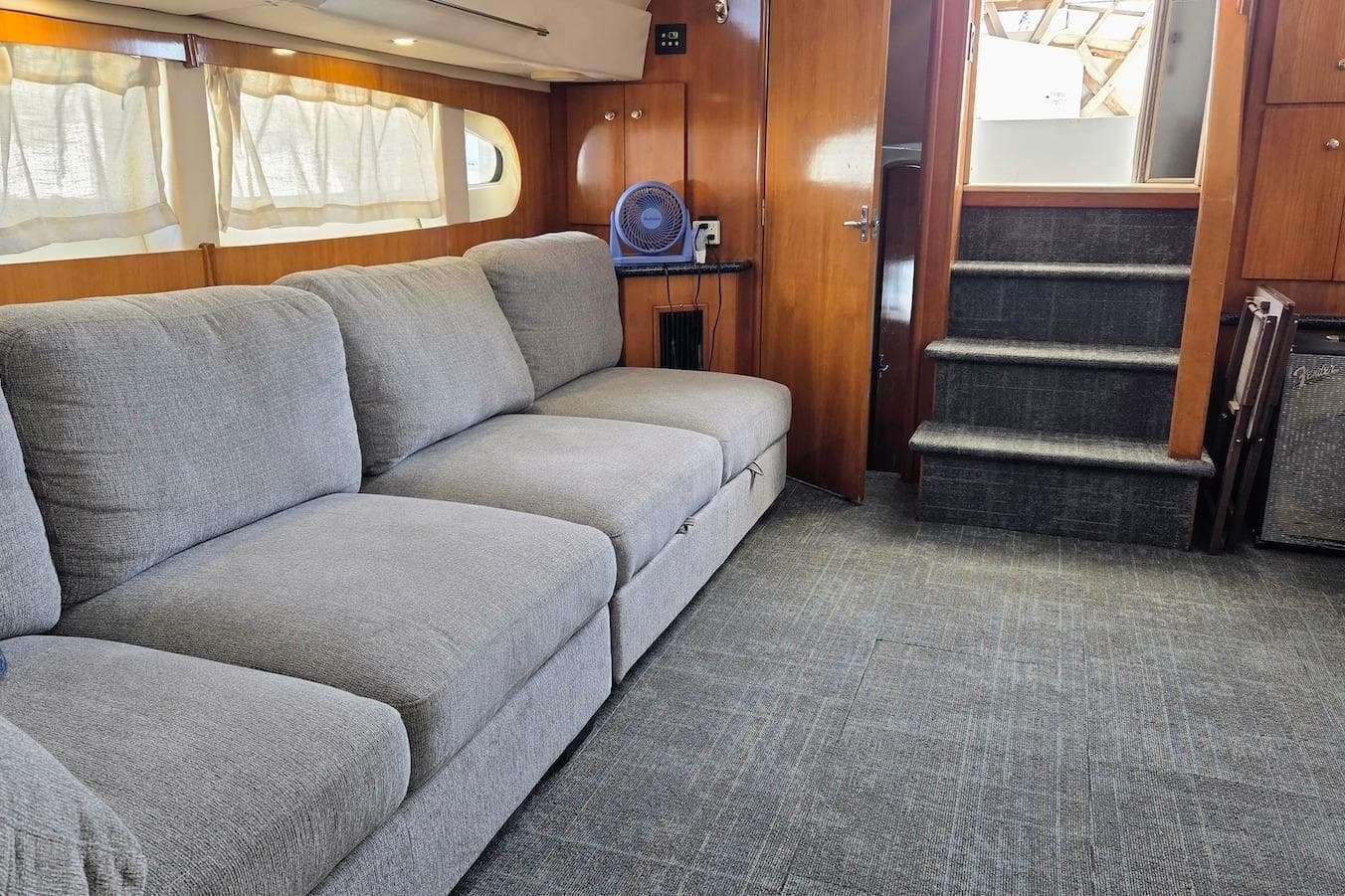 Interior of 2000 Carver 396 Motor Yacht with gray sofa and carpeted stairs.