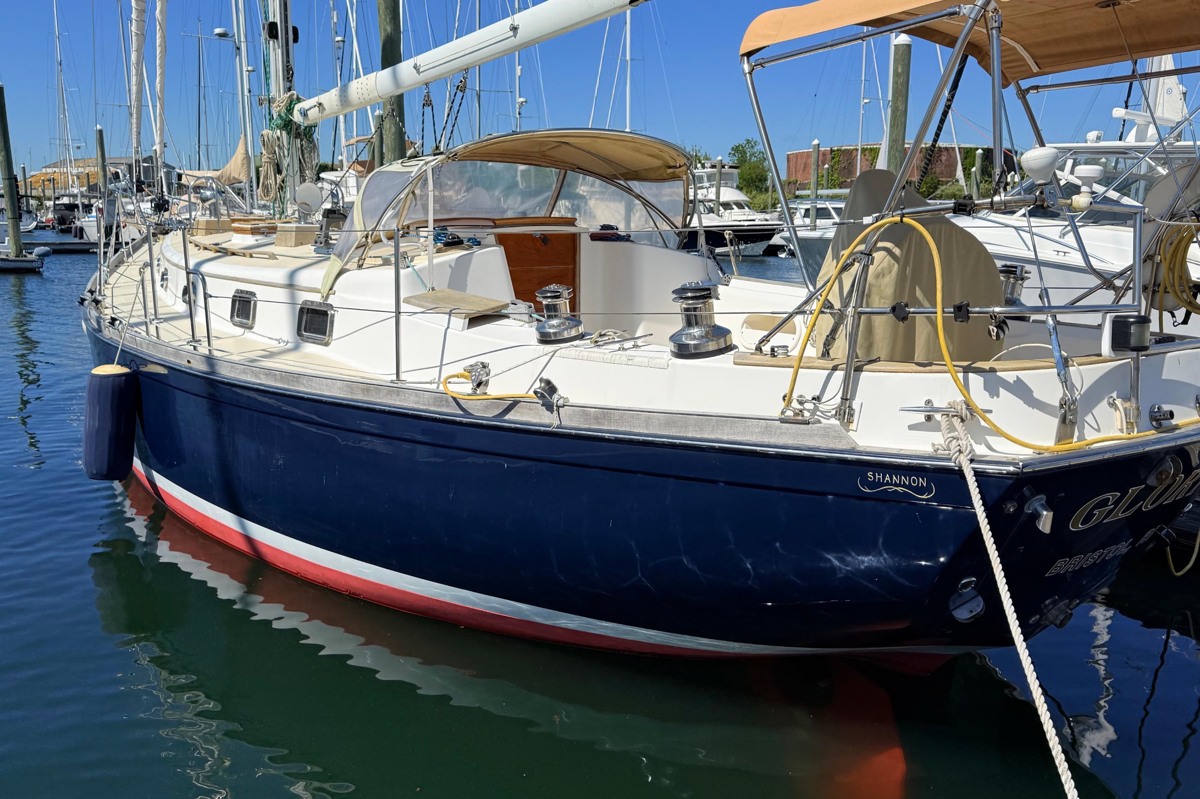 Sailboat docked in marina, 2001 Shannon 43 Cutter, blue hull, sunny day.
