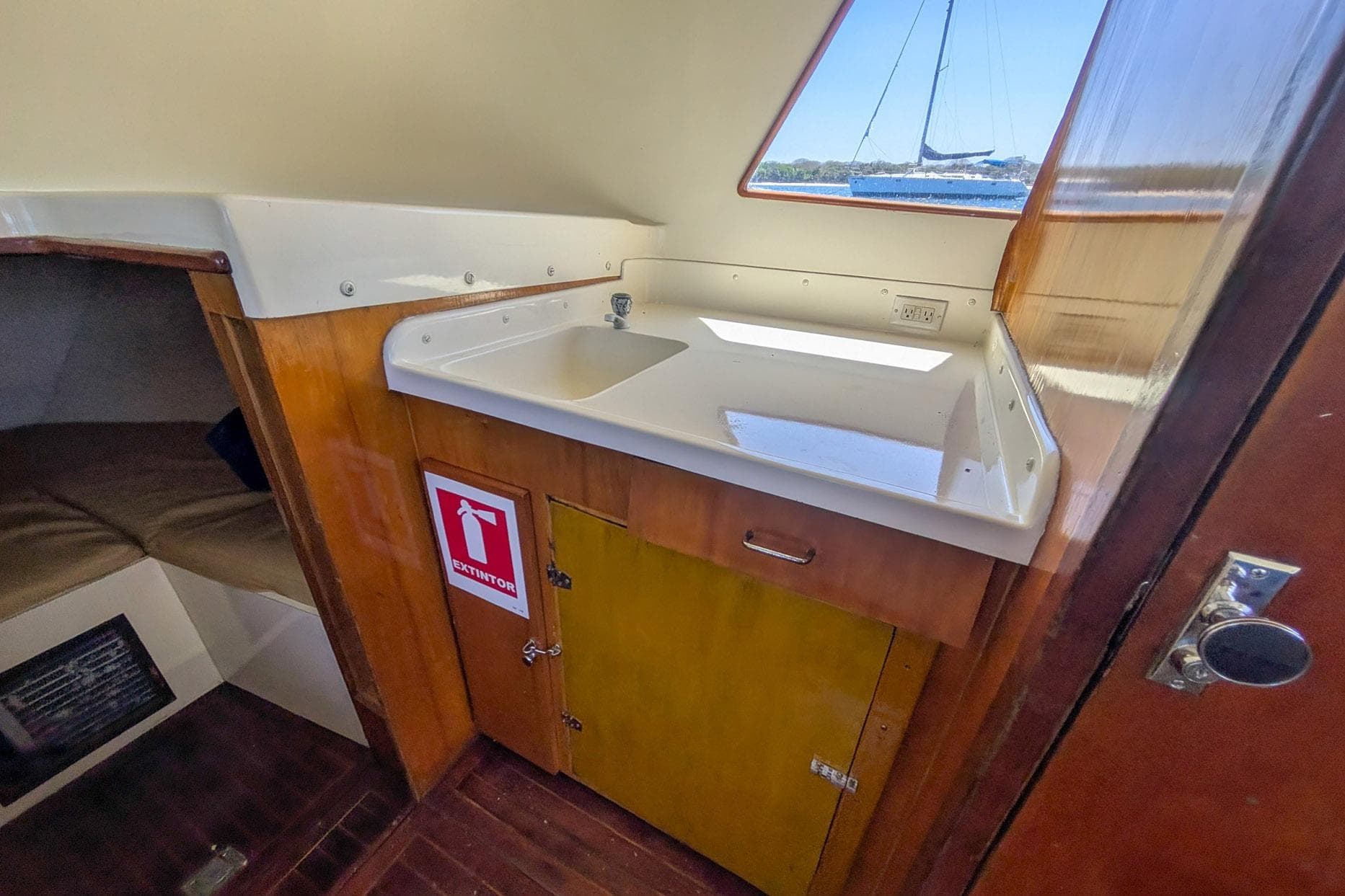 1973 Bertram 31 Sportfisher interior with sink, wooden cabinetry, and fire extinguisher sign.