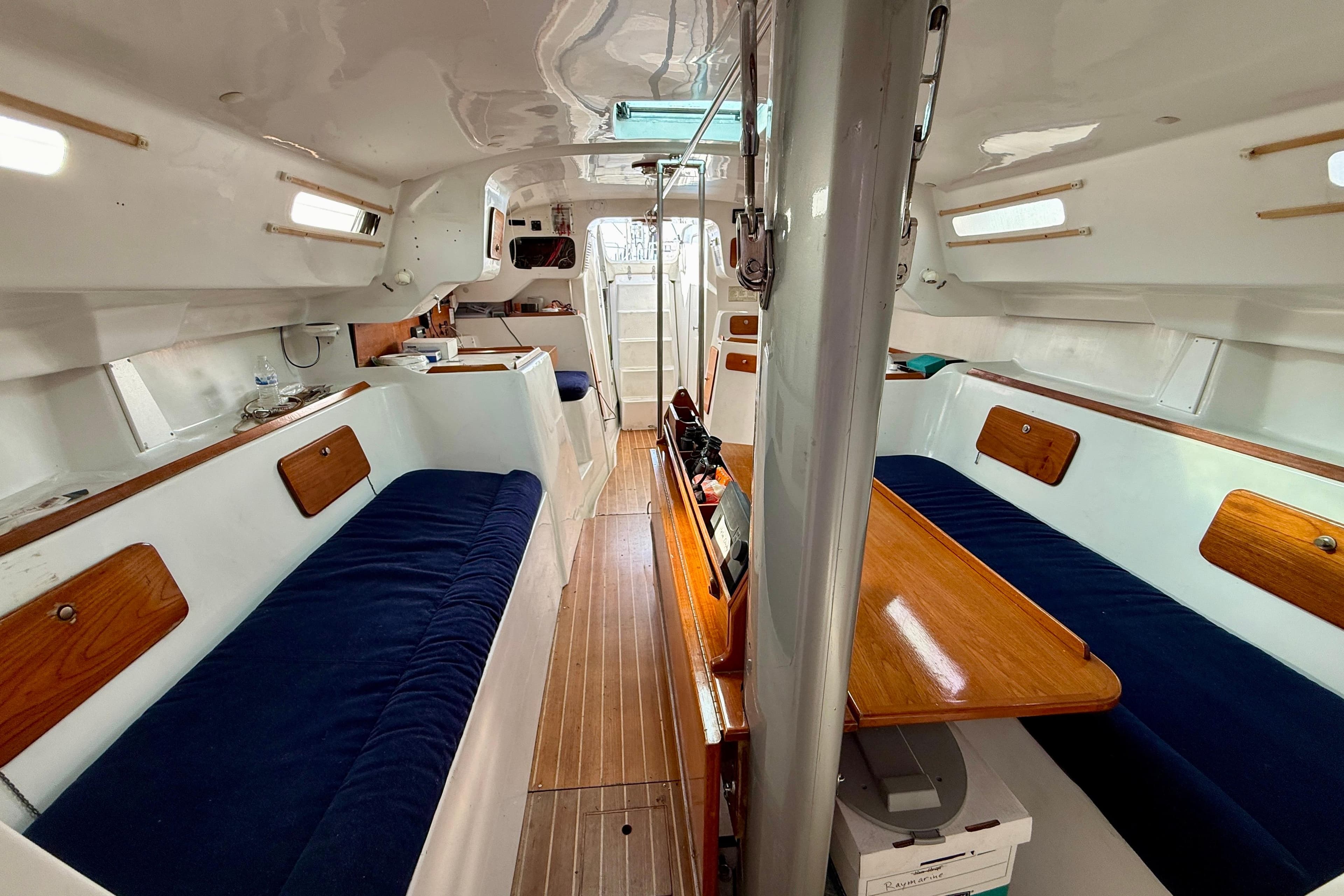 Interior of a 1985 MacGregor 65 sailboat with blue seating and wooden accents.