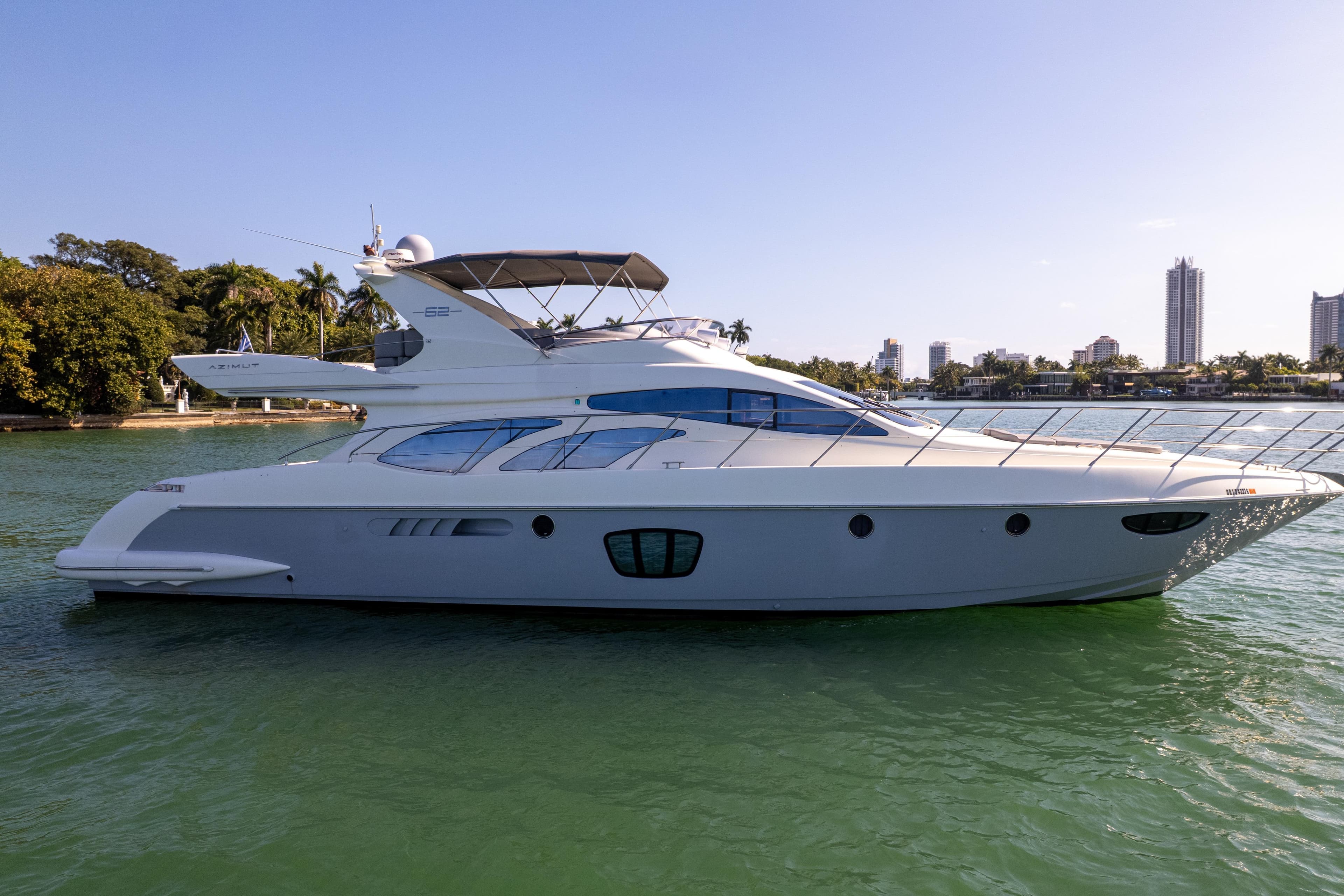 2008 Azimut 62E yacht on calm water with city skyline background.