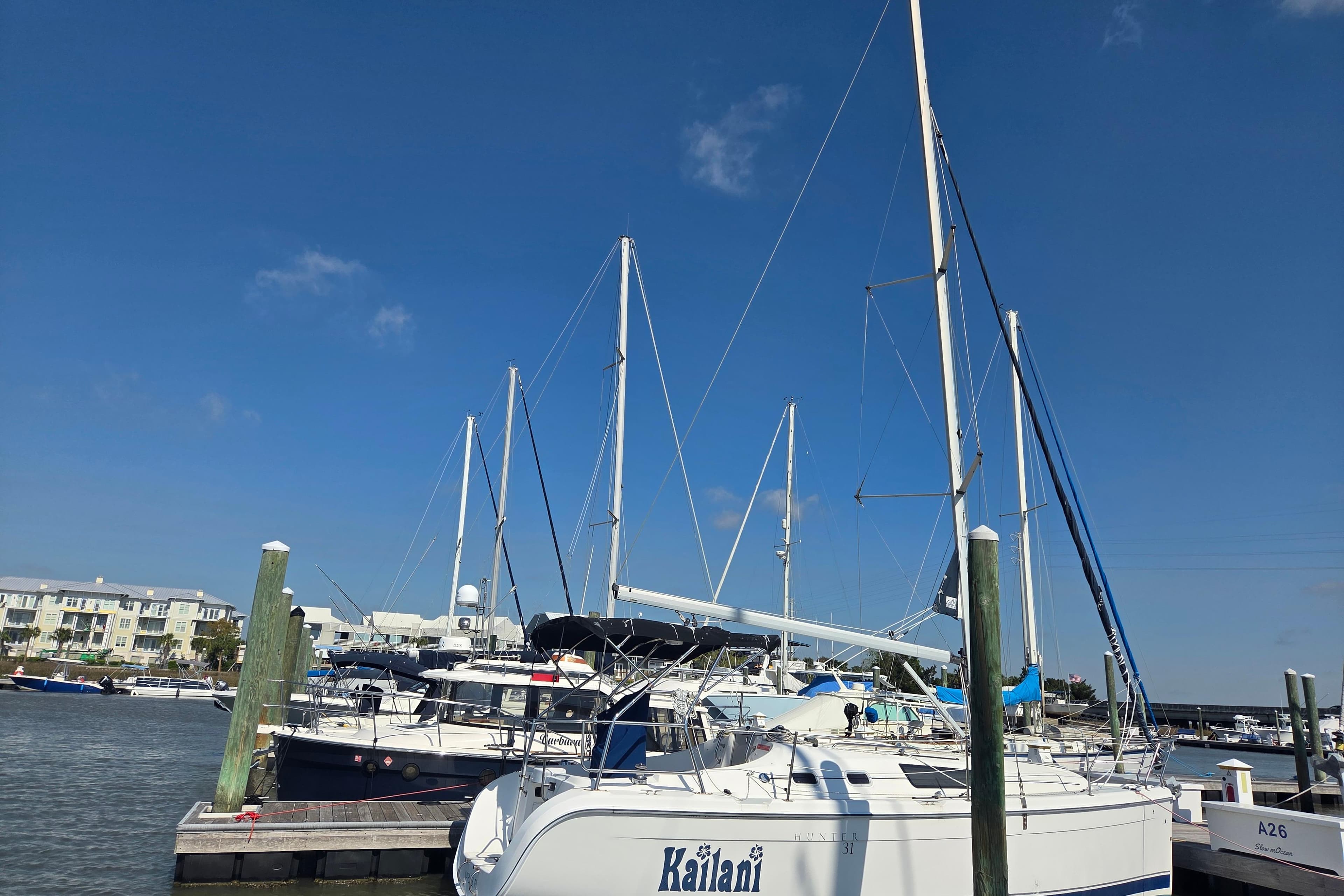 Sailboats docked at a marina under a clear blue sky, featuring a 2005 Hunter 31.