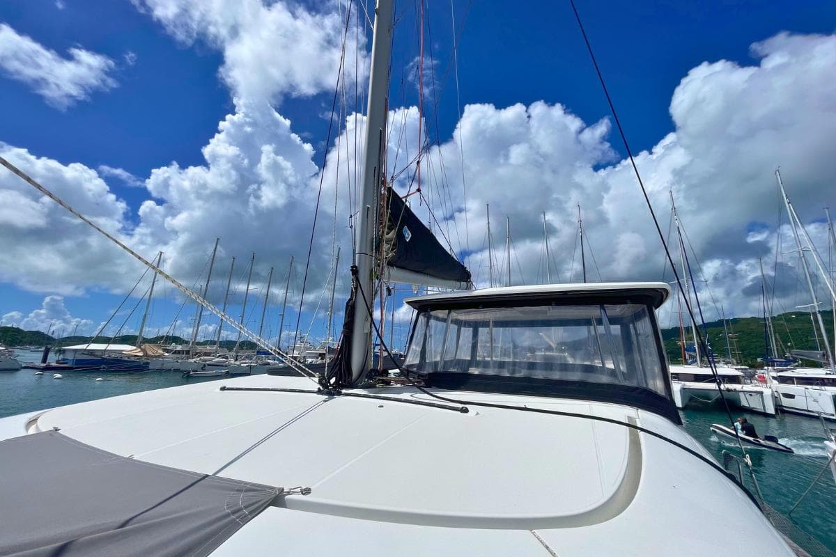2018 Lagoon 42 catamaran docked under a vibrant blue sky with fluffy clouds.