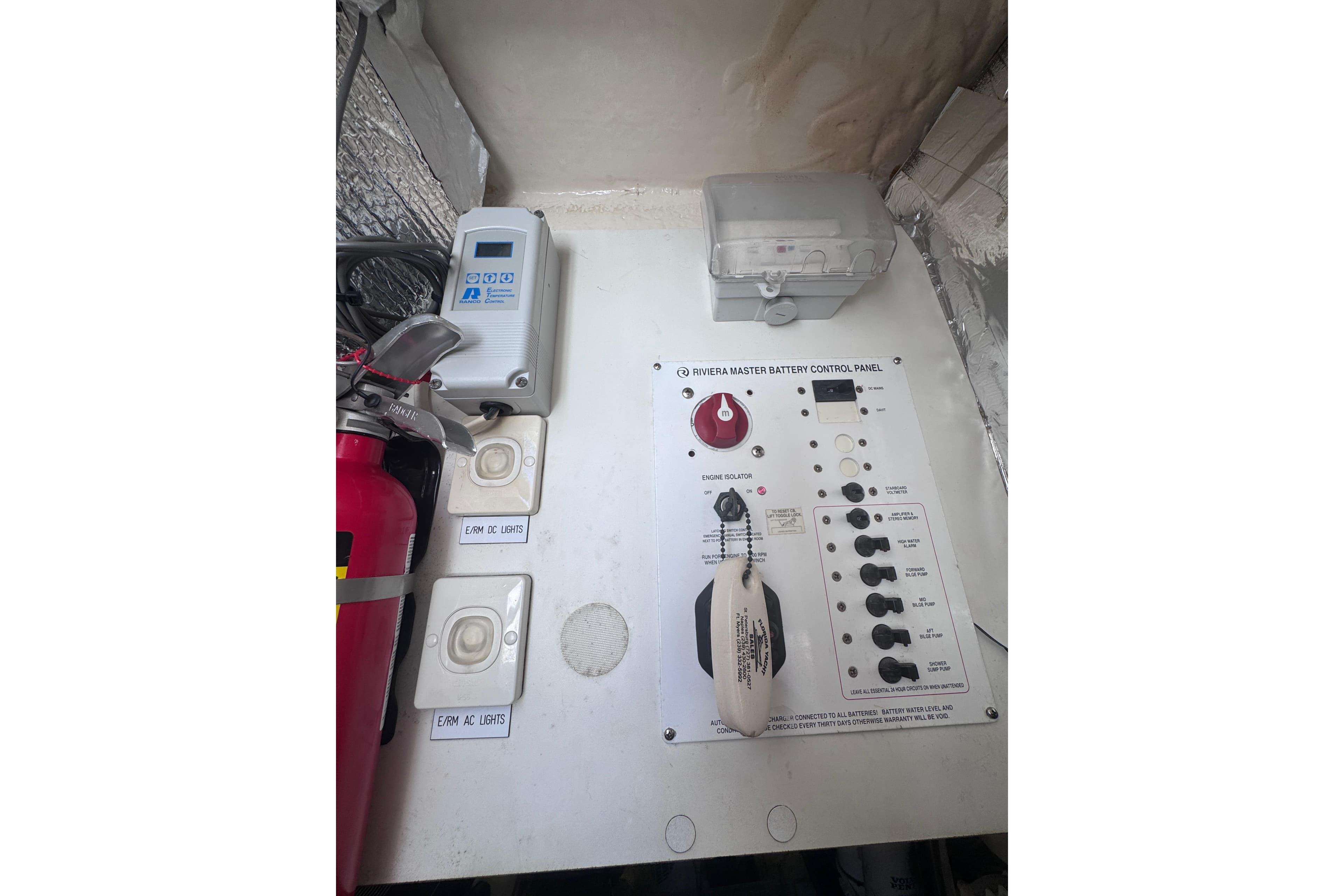 Control panel of a 2006 Riviera 37 Flybridge boat with switches and fire extinguisher.