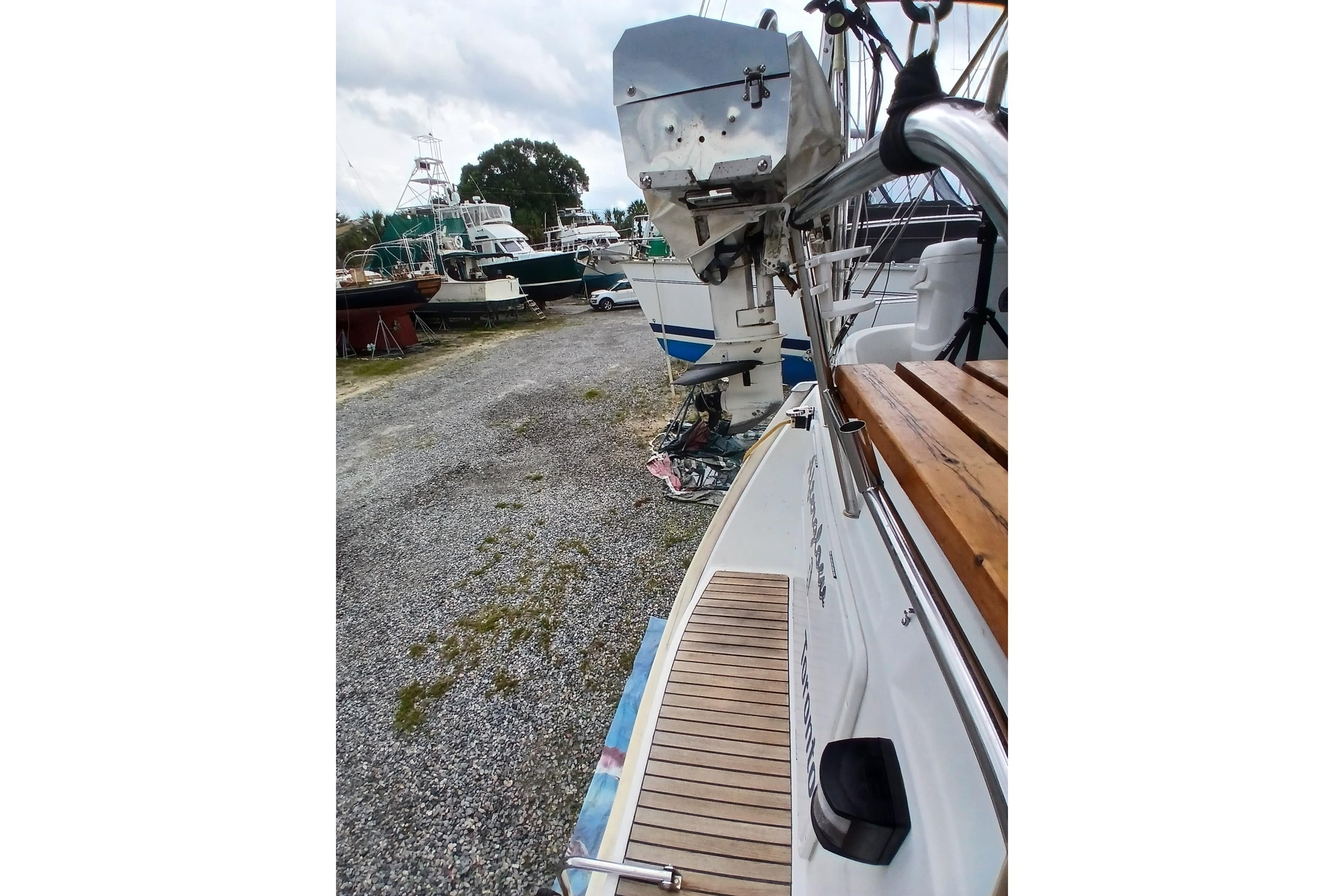 2002 Jeanneau Sun Odyssey 43 DS sailboat on gravel, with visible deck and outboard motor.