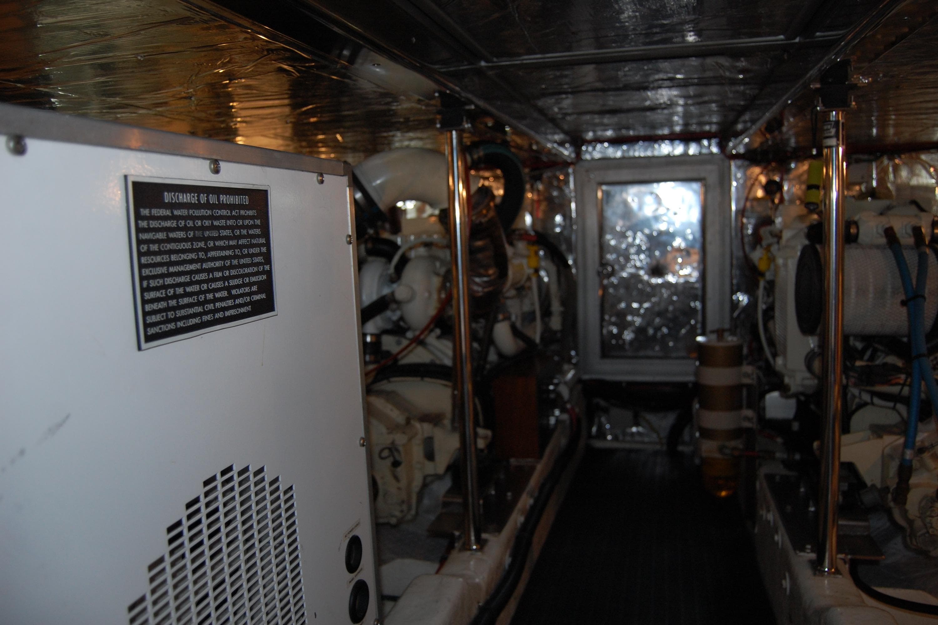 Engine room of 2001 Ocean Alexander Classico yacht, featuring machinery and safety signage.