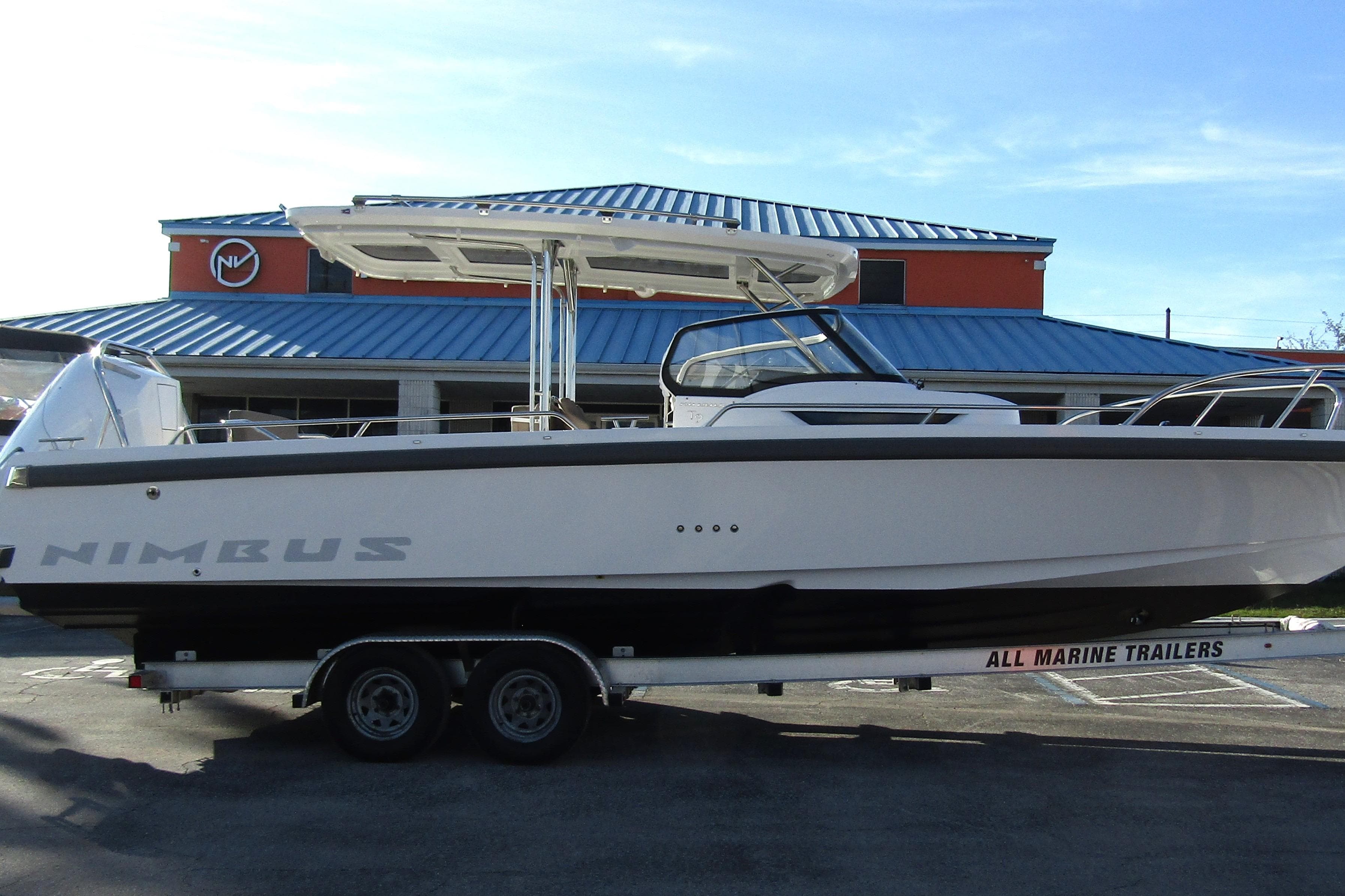 2025 Nimbus Tender 9 boat on trailer, parked outside a building with blue roof.