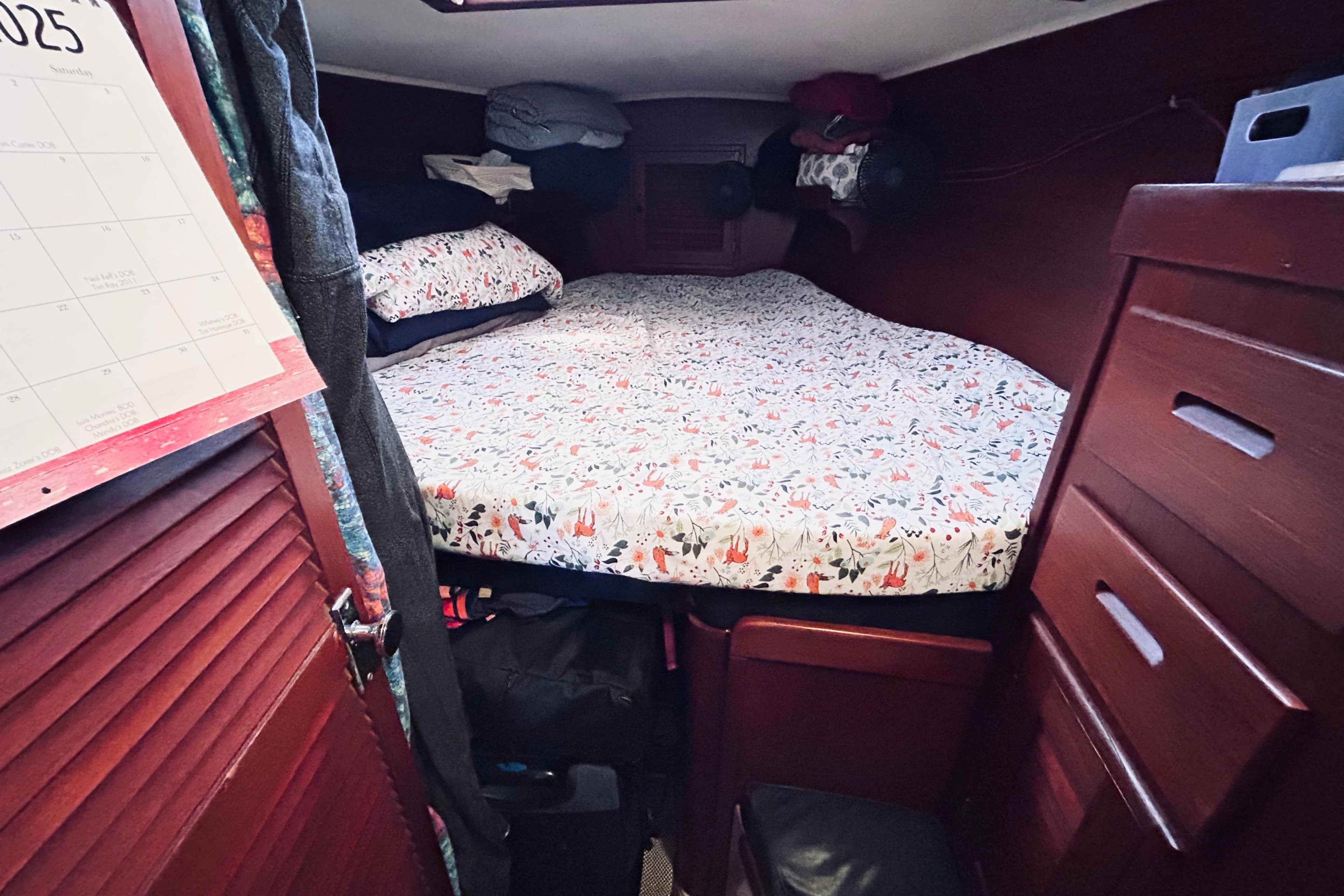 Cozy cabin interior of 1983 Tartan 42 sailboat with floral bedding and wooden storage.