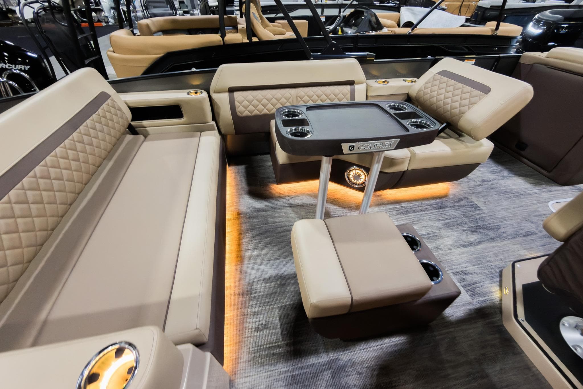 Luxurious interior of 2025 Godfrey AquaPatio 25' Flip Lounge Tritoon with plush seating and table.