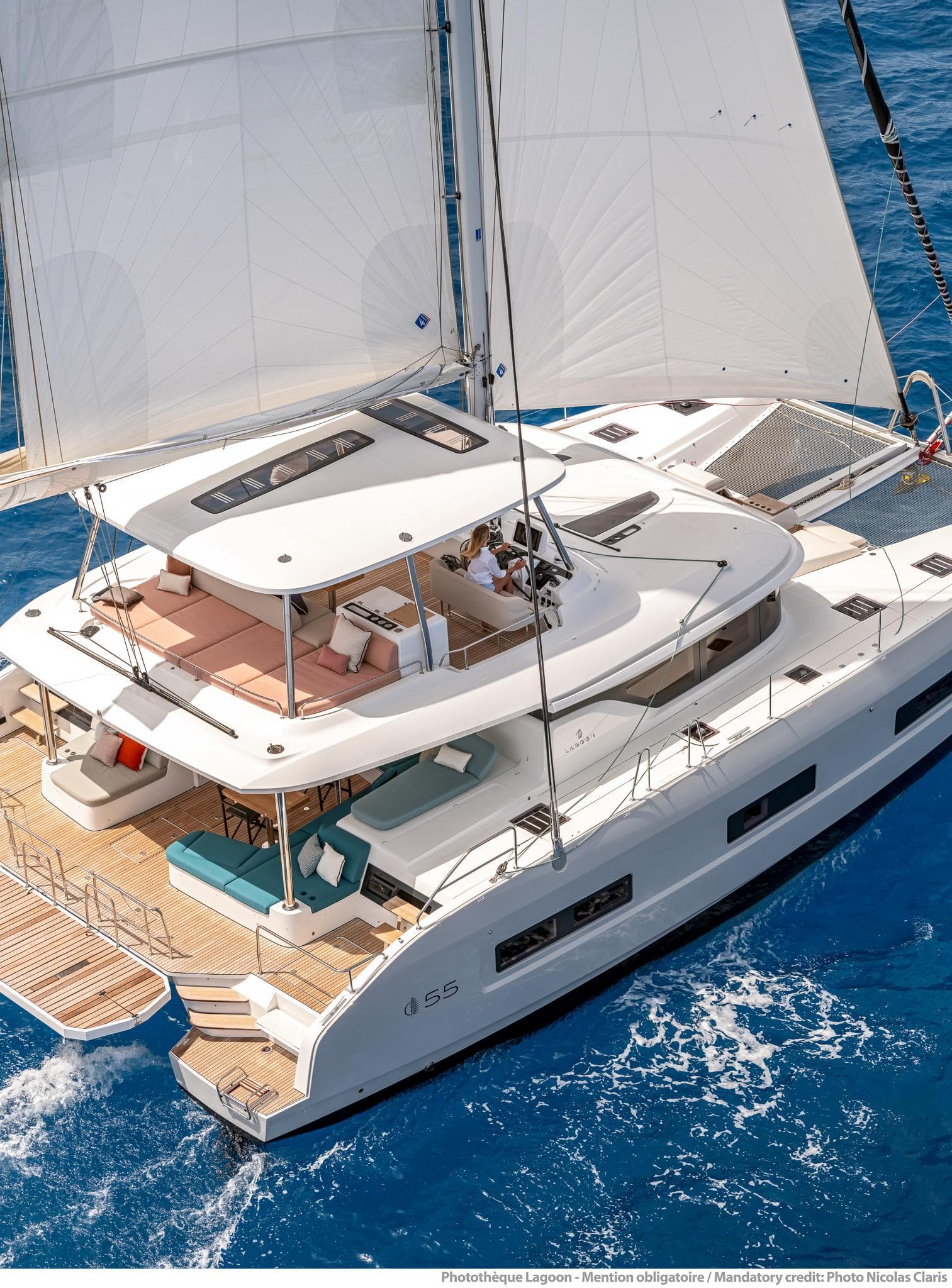 2025 Lagoon 55 catamaran sailing on blue ocean waters, showcasing luxury and modern design.