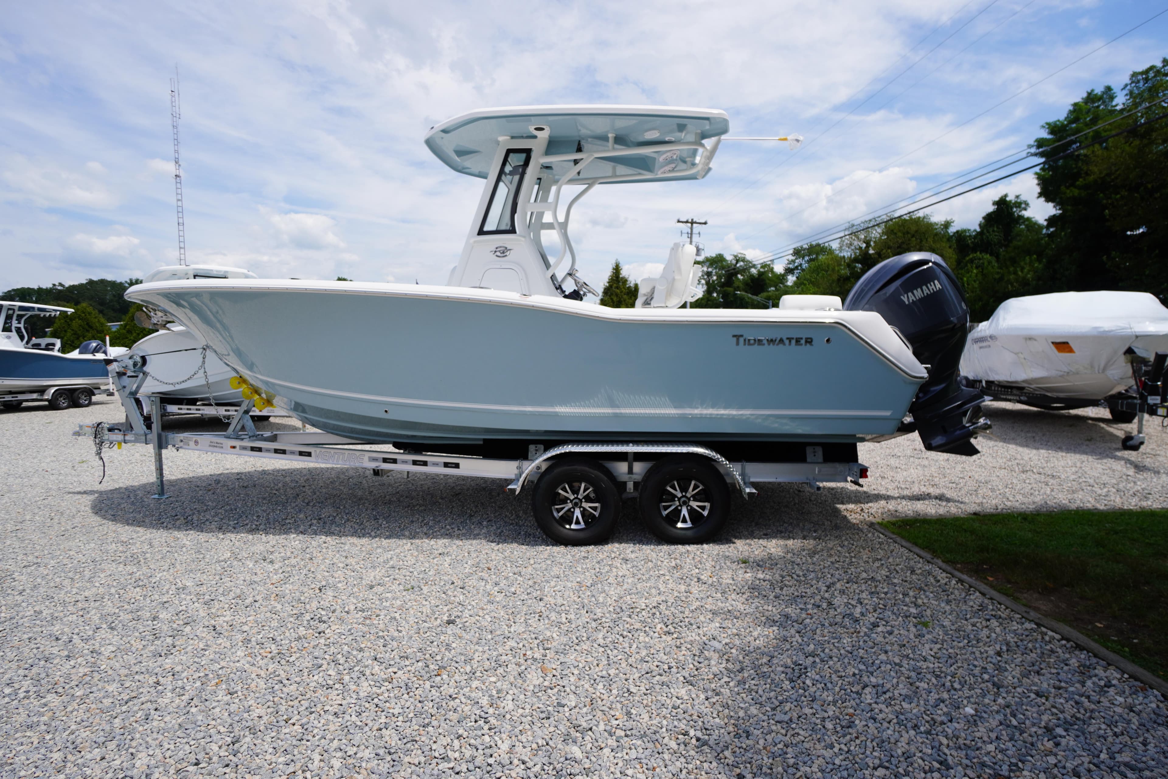 2026 Tidewater 232 SS boat on trailer, parked on gravel lot under blue sky.