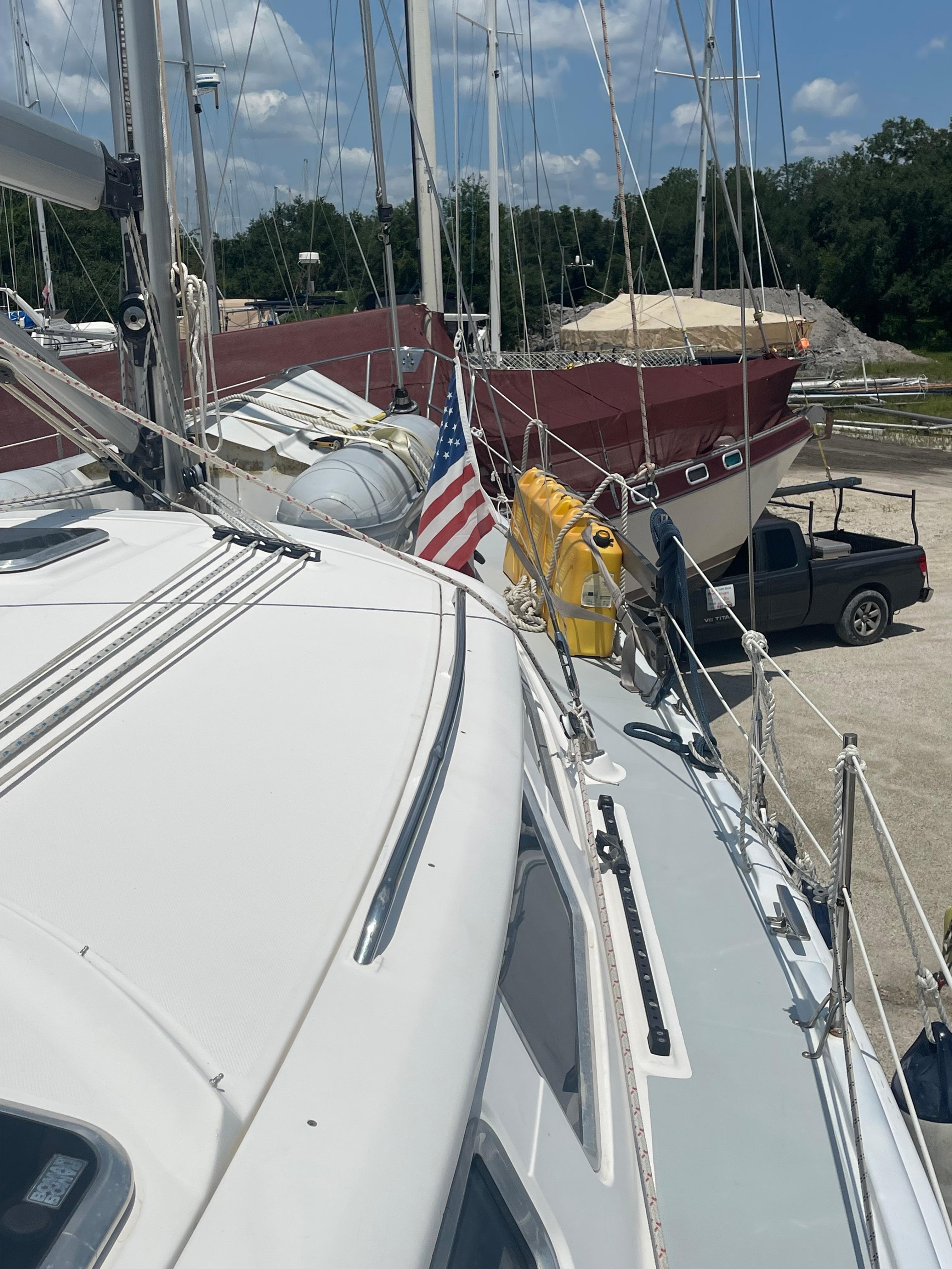 Hunter 44 DS Deck Salon 2004 sailboat on land, with American flag and nearby vehicles.