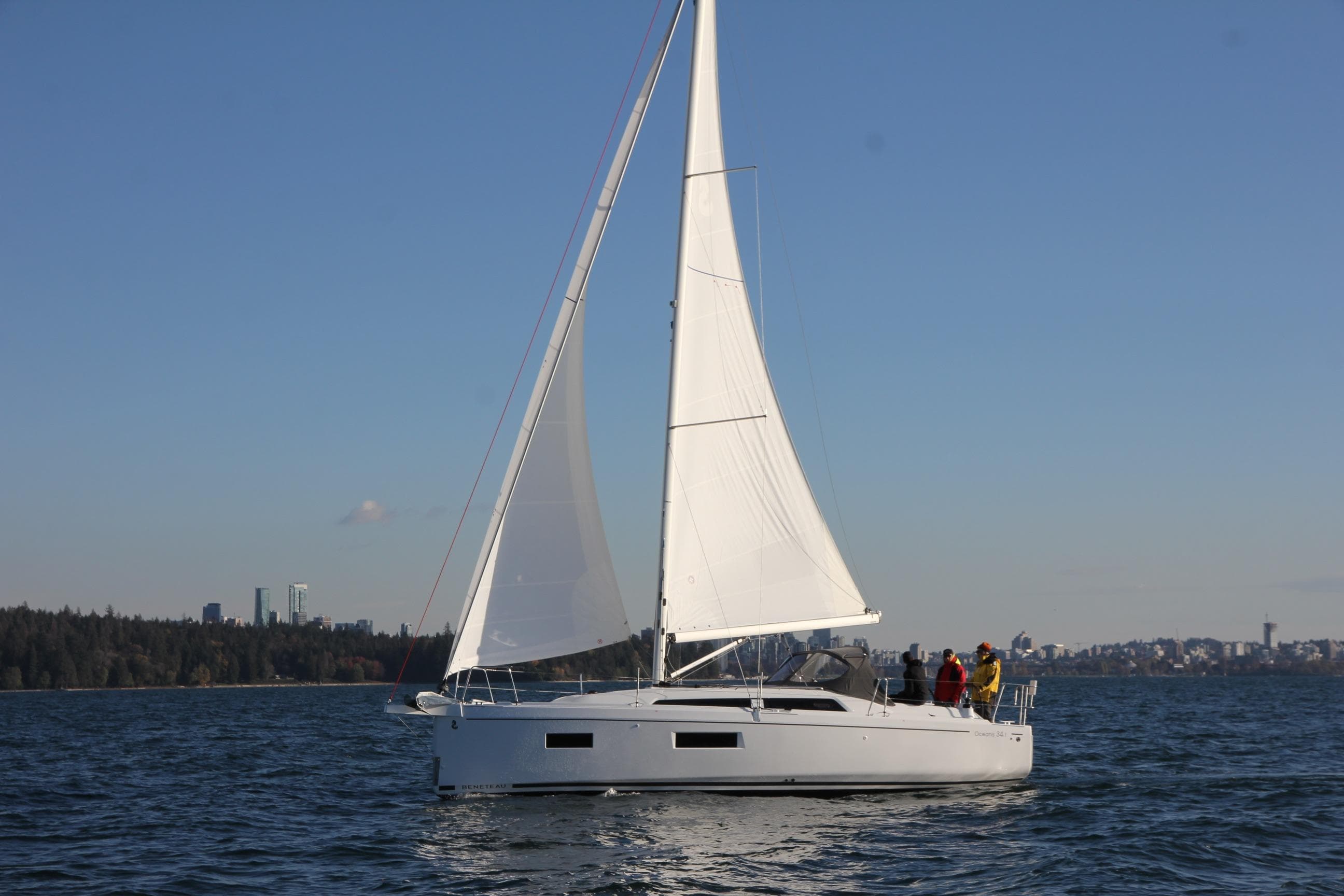 2023 Beneteau Oceanis 34.1 sailing on open water with city skyline in background.