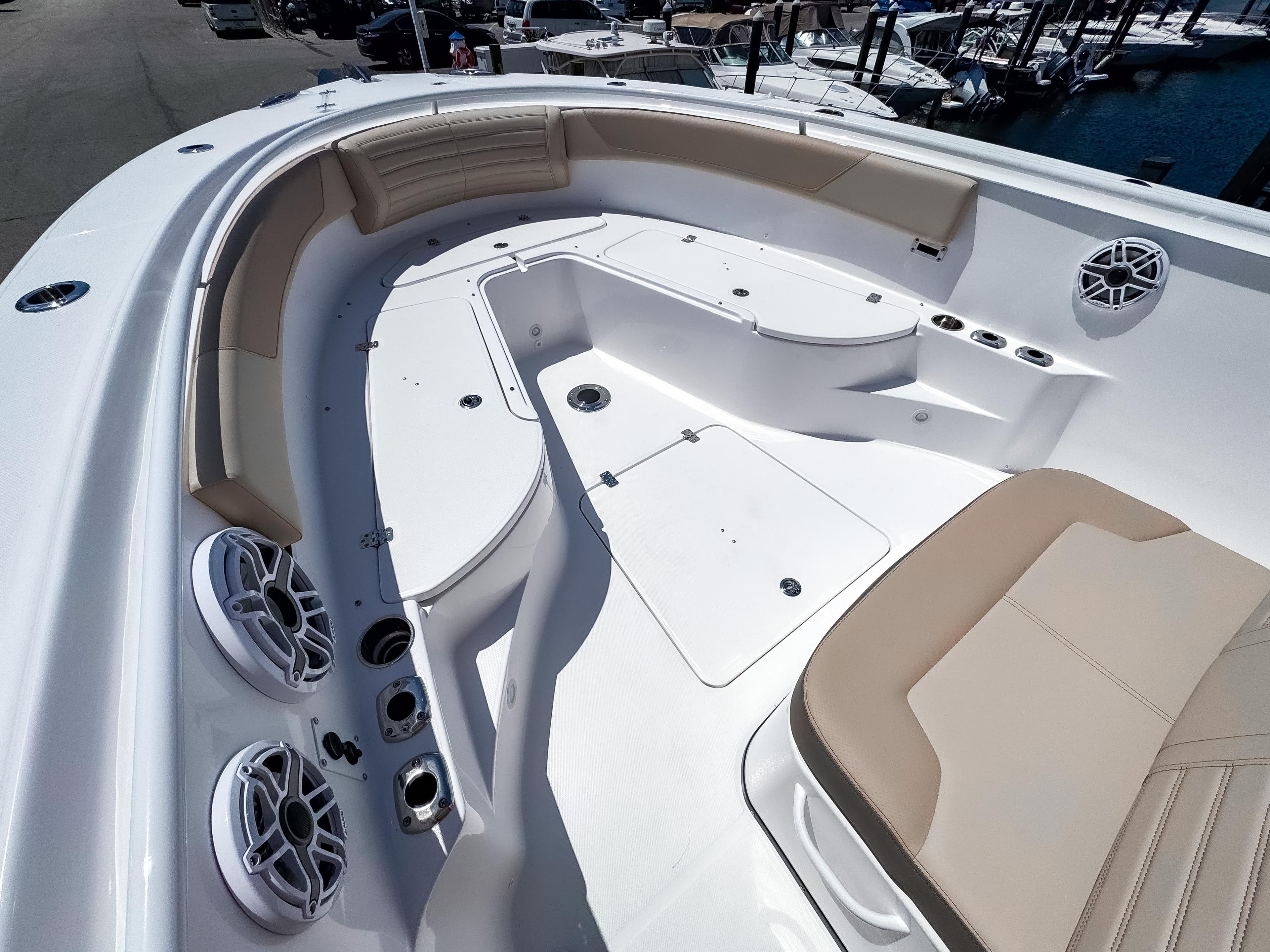 2025 Edgewater 325CC boat interior with beige seating and speakers, docked at a marina.