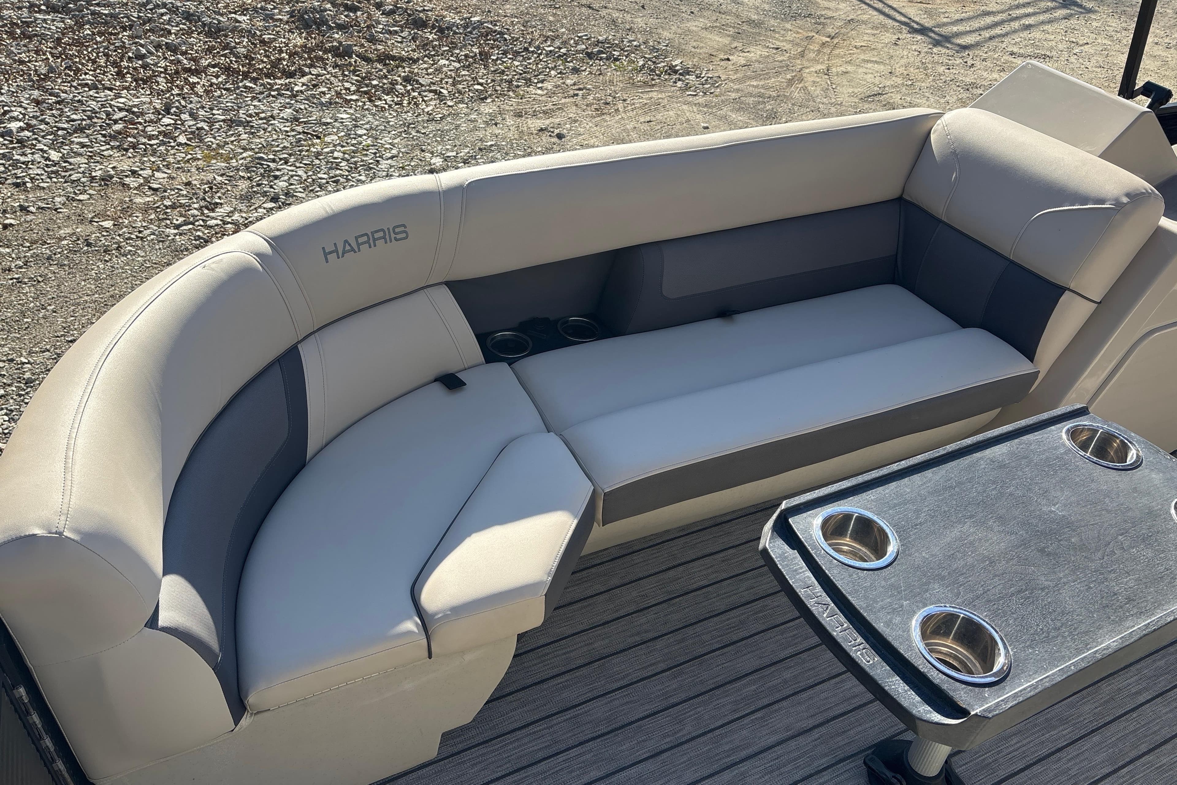 2023 Harris Cruiser 230 boat interior with cushioned seating and table with cup holders.