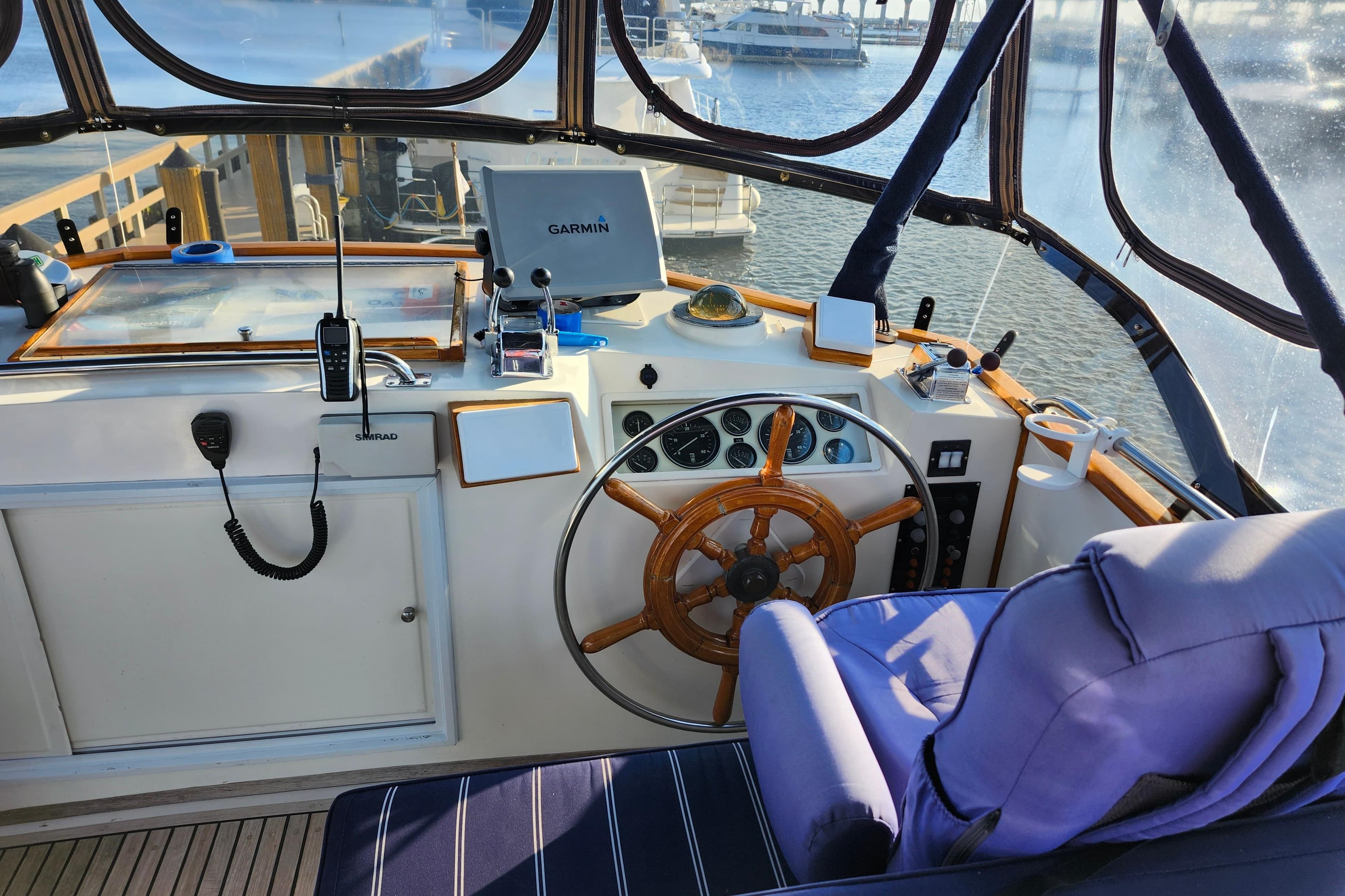 Helm of 1991 Grand Banks 42 Classic yacht with navigation equipment and wooden steering wheel.