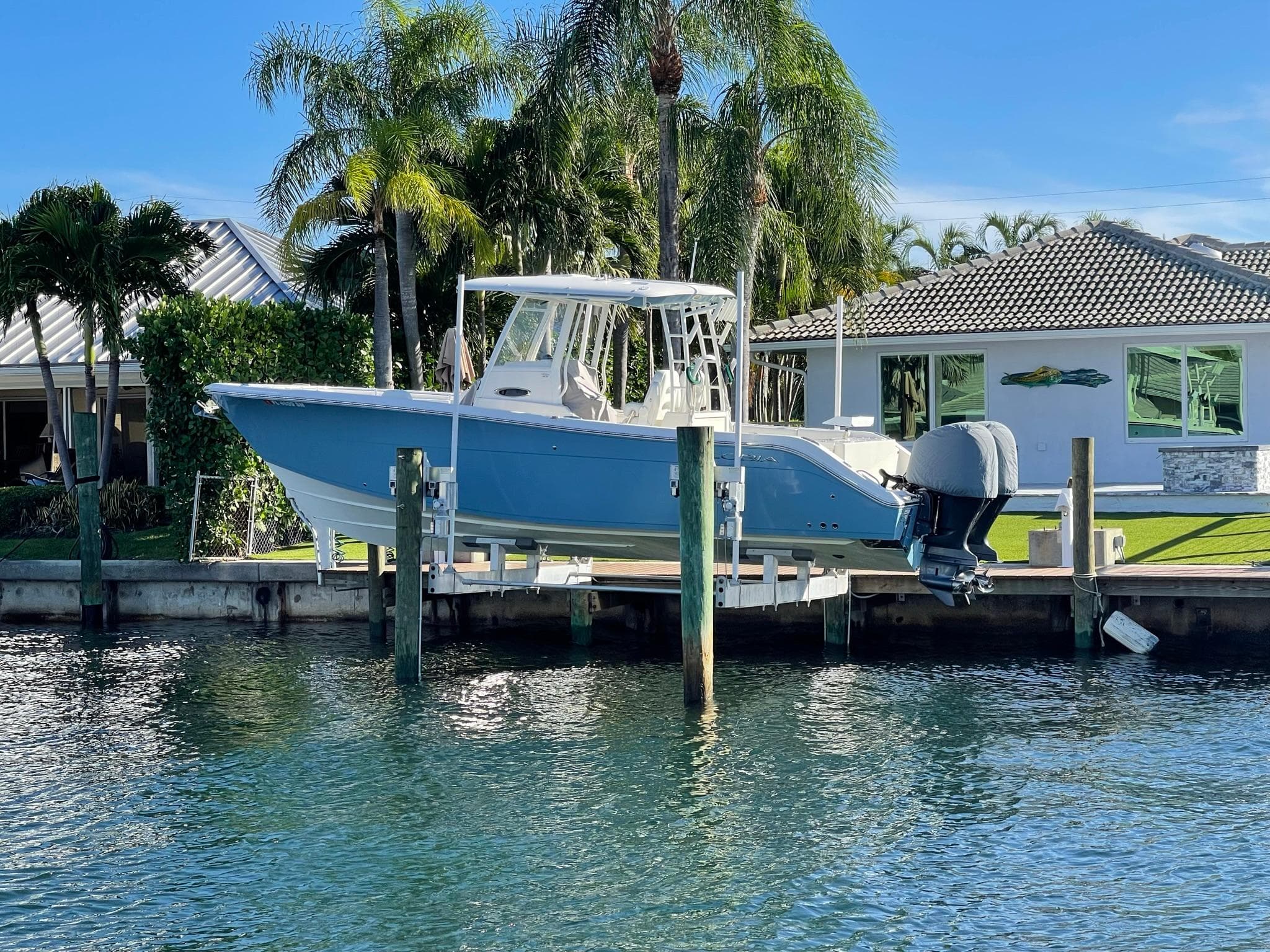 2020 Cobia 301 Center Console boat docked by tropical house.
