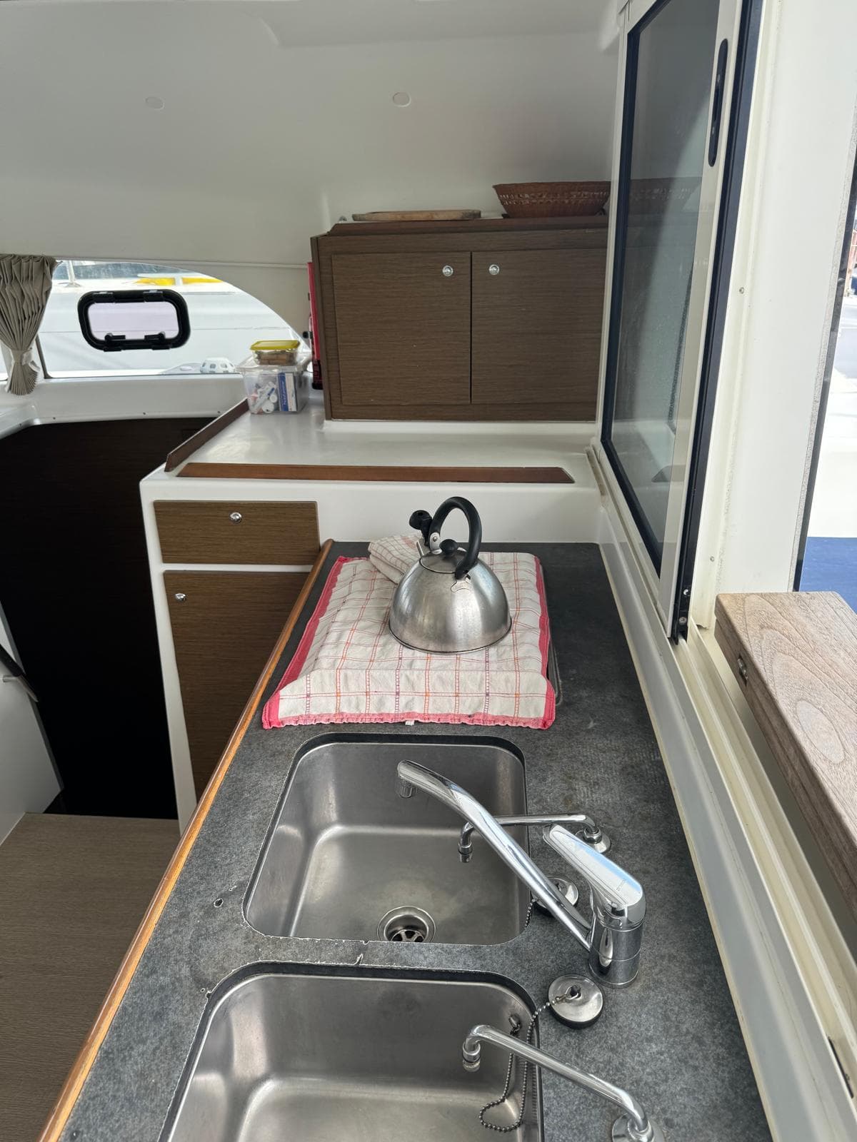 Interior of 2018 Lagoon 380 catamaran kitchen with sink, kettle, and storage cabinets.