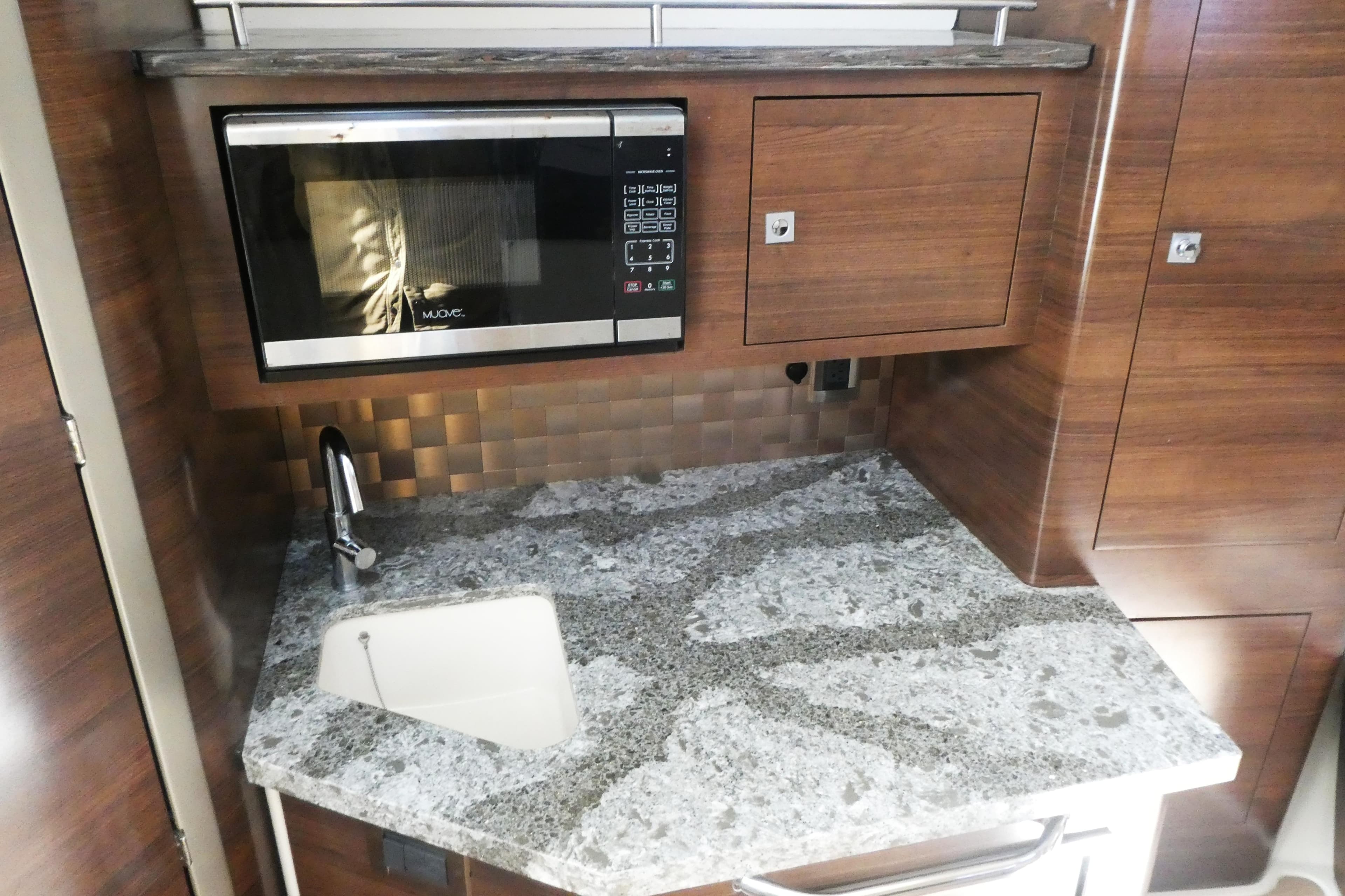2020 Boston Whaler 345 Conquest galley with granite countertop, sink, and microwave.