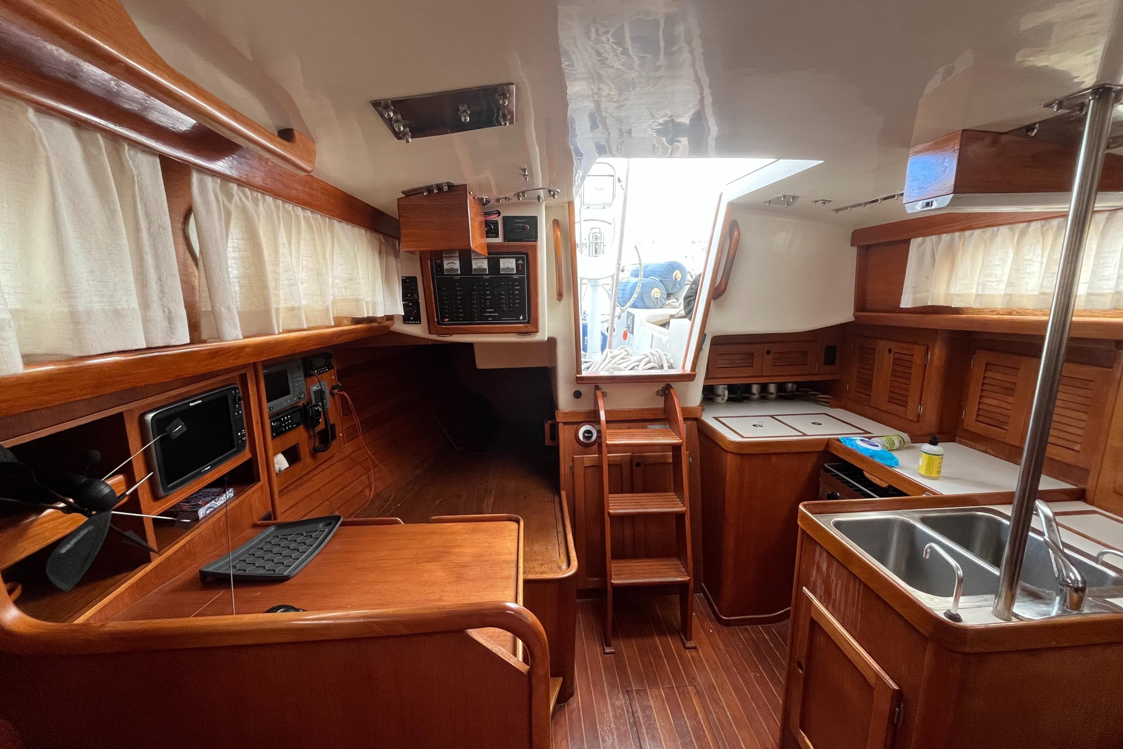 Interior of a 1986 Bristol 38.8 sailboat, featuring wood finishes and a compact kitchen.