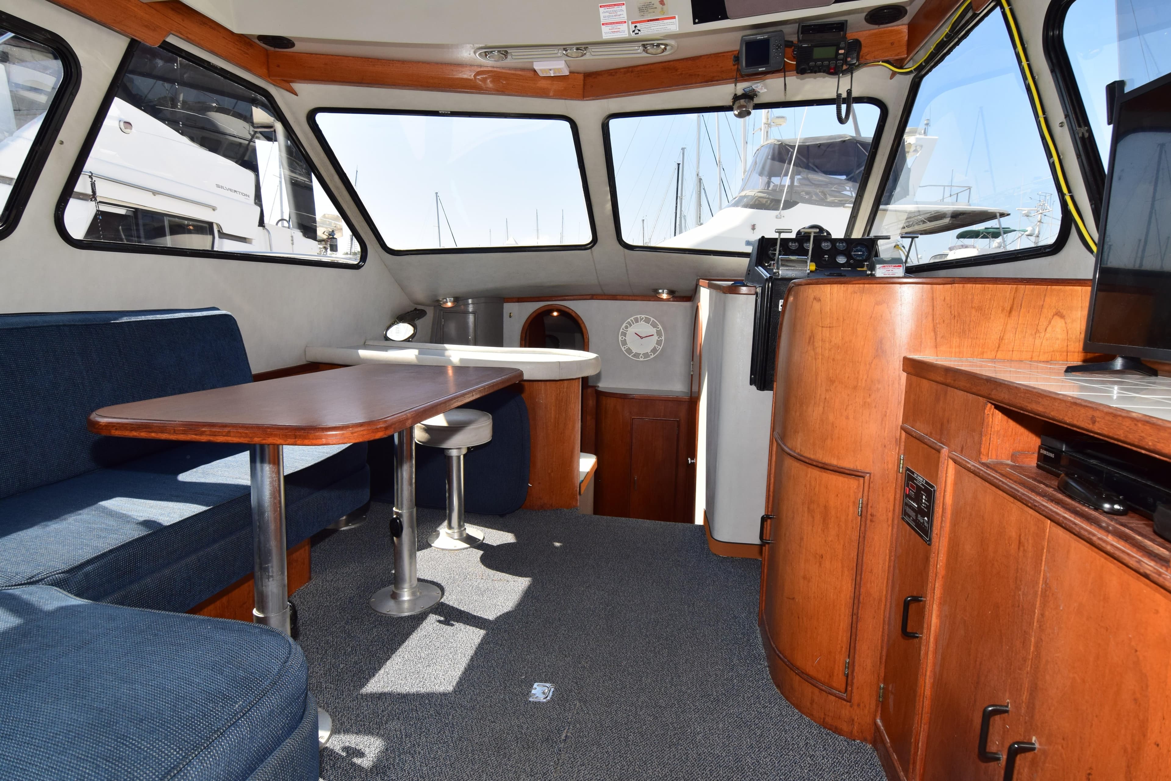 Interior of 1988 Mediterranean 38 Convertible yacht with seating, table, and wooden cabinetry.