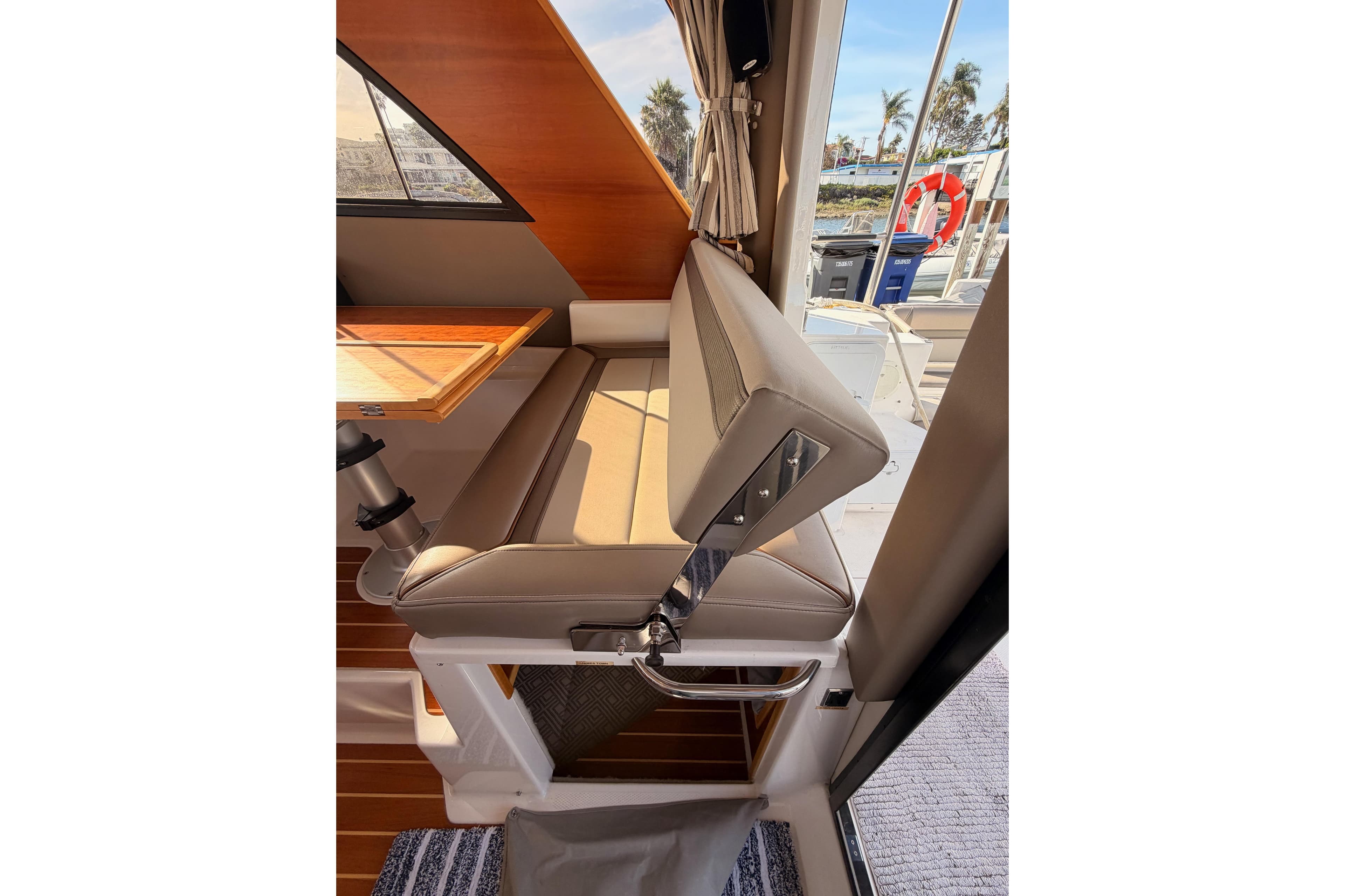 2021 Cutwater C-32 CB interior with beige seating and wooden table, dockside view.